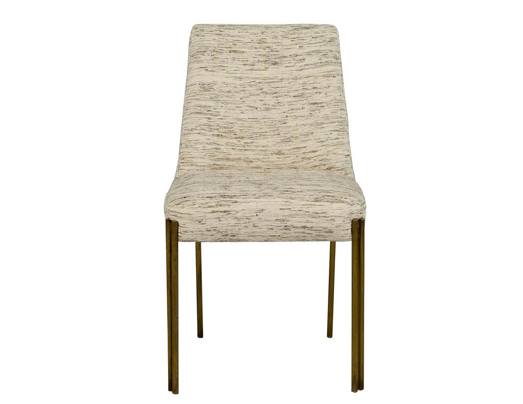 These modern dining chairs by Kelly Wearstler are a lesson in the current gilded trend. They are crafted in the Parsons style and upholstered with a woven, creamy white fabric speckled with sandy beige thread throughout. To add contrast, they sit