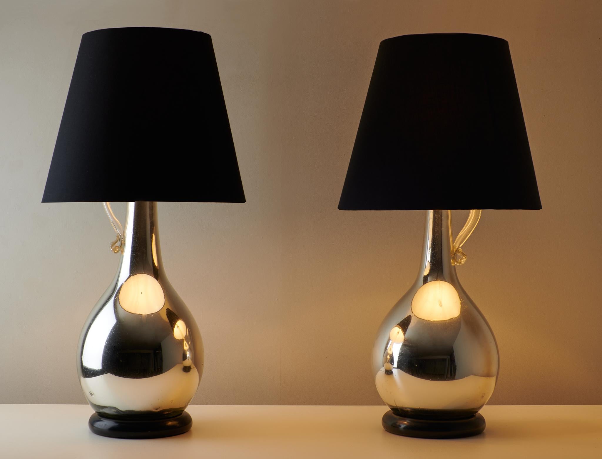 Élégante et lumineuse, cette paire de lampes en verre au mercure présente une finition doucement réfléchissante qui capture et diffuse magnifiquement la lumière. Le couple offre un mélange de charme vintage et de glamour.
