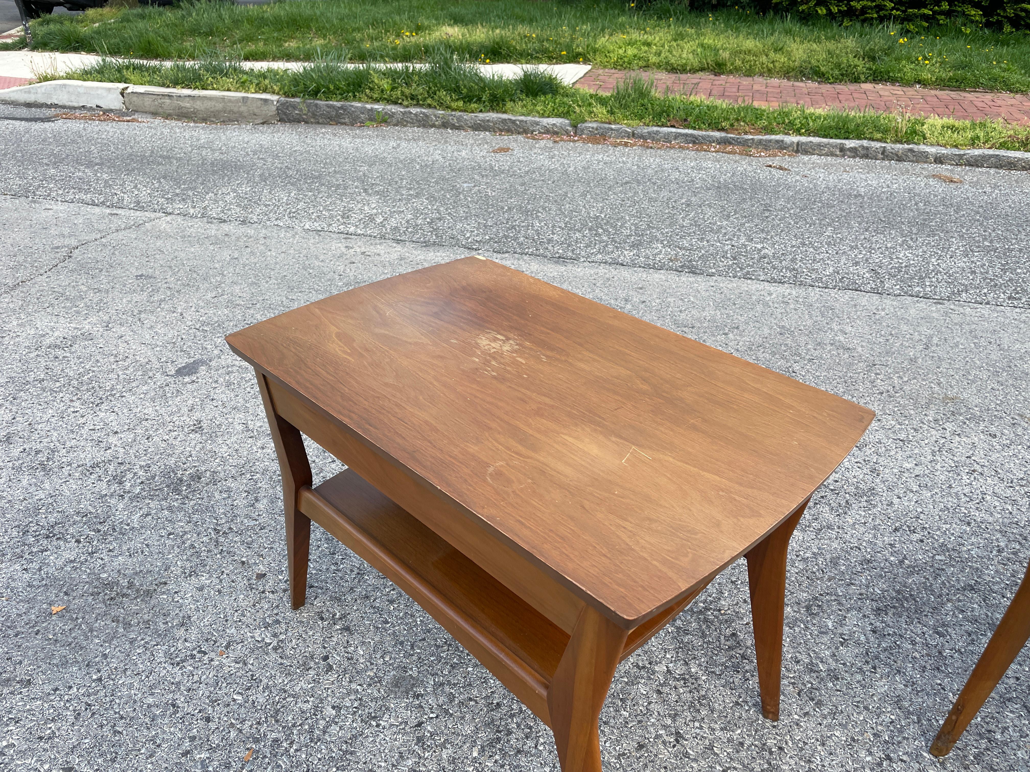 A great pair of 1960s midcentury end tables with under-shelves and drawers by Mersman. Some wear from age and use but overall sturdy and ready for use. I can have these refinished if the customer desires. Message for a quote.

Each table measures
