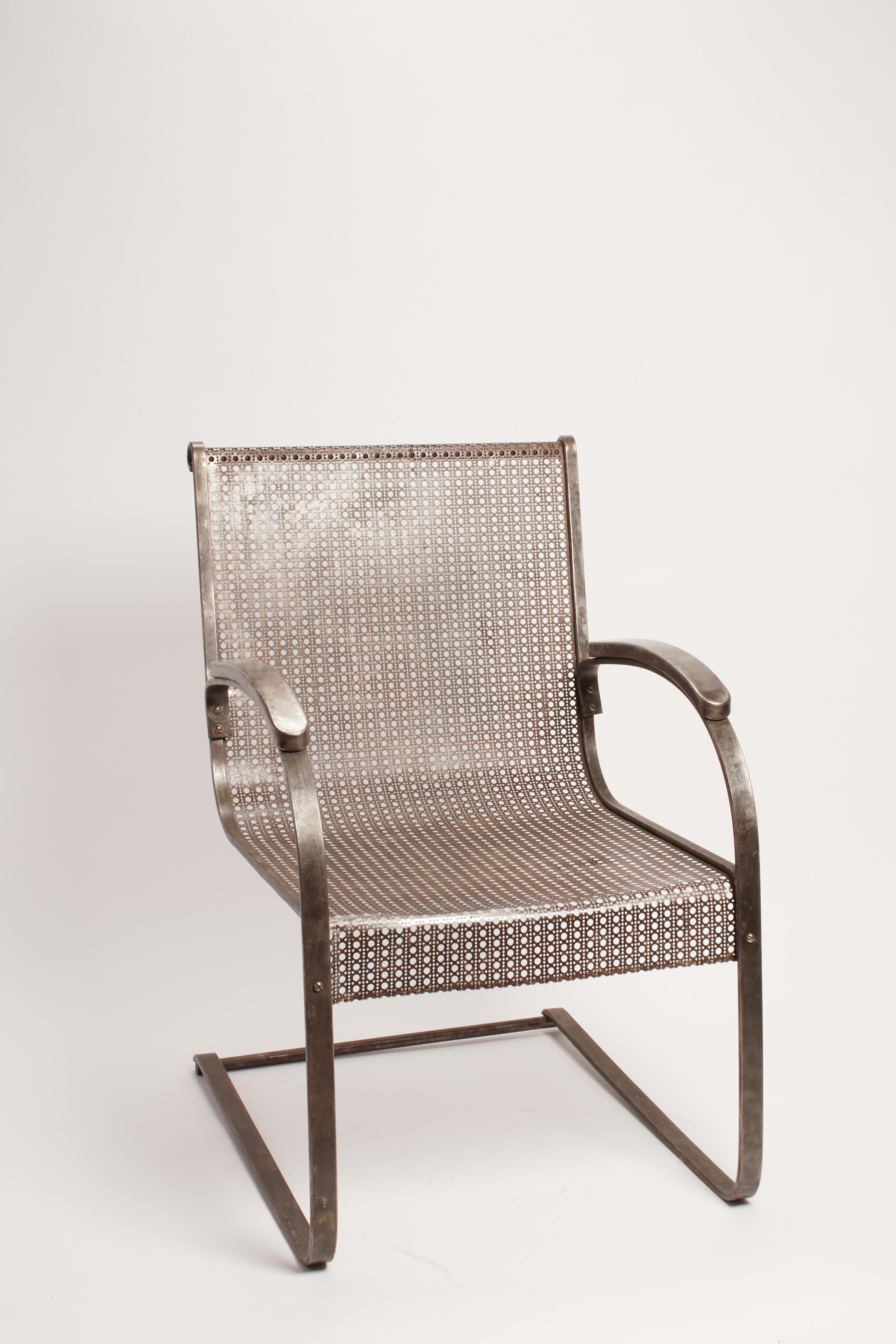 Pair of iron armchairs with perforated sheet used as support for back and seat. Equipped with armrests. USA 1930 ca.