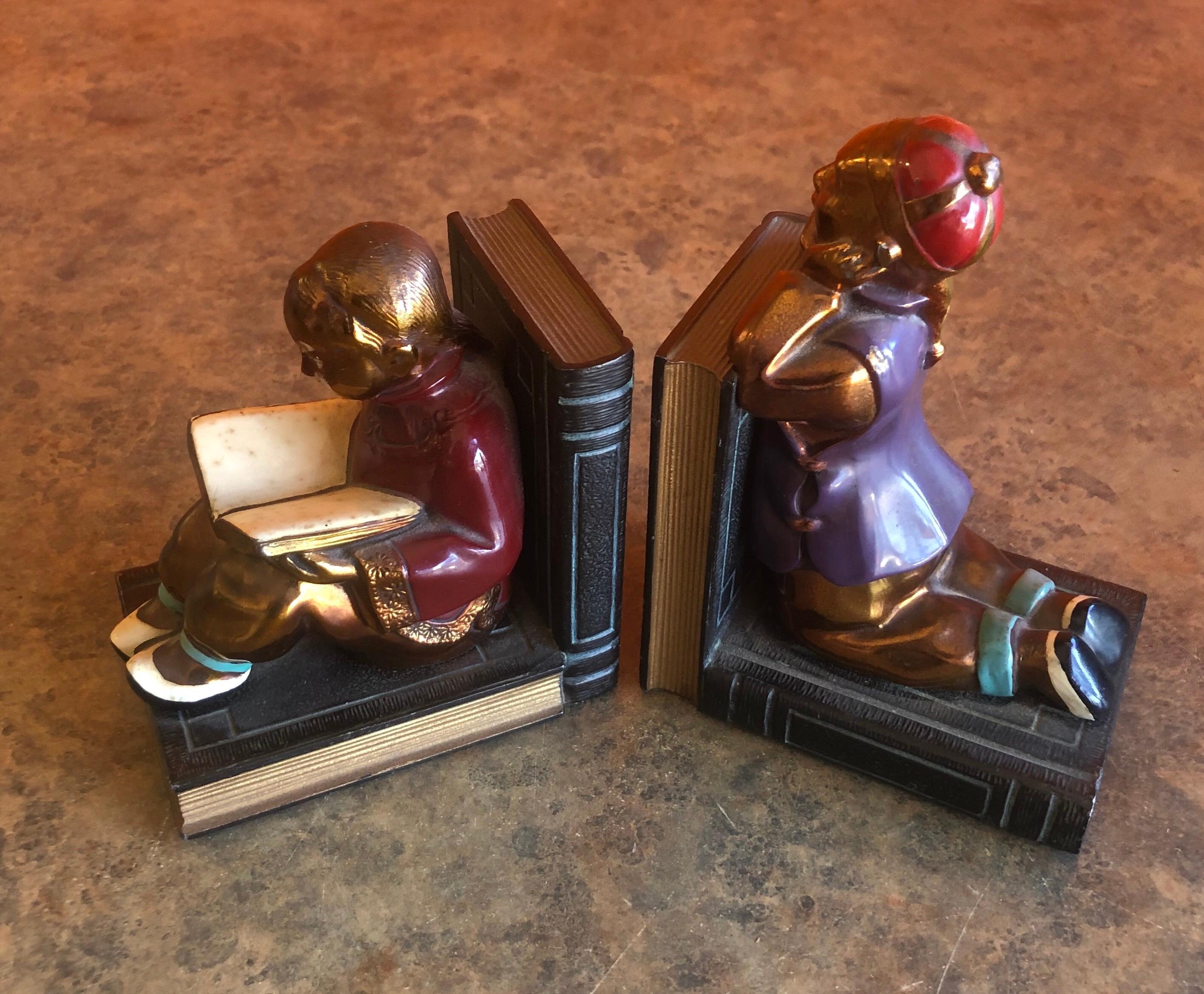 Fabulous pair of metal clad Art Deco bookends by Ronson Art Metal Works, circa 1930s. The bookends depict two Chinese youngsters, beautifully sculpted; the boy is patiently observing while the girl is quietly absorbed by what she reads.

This