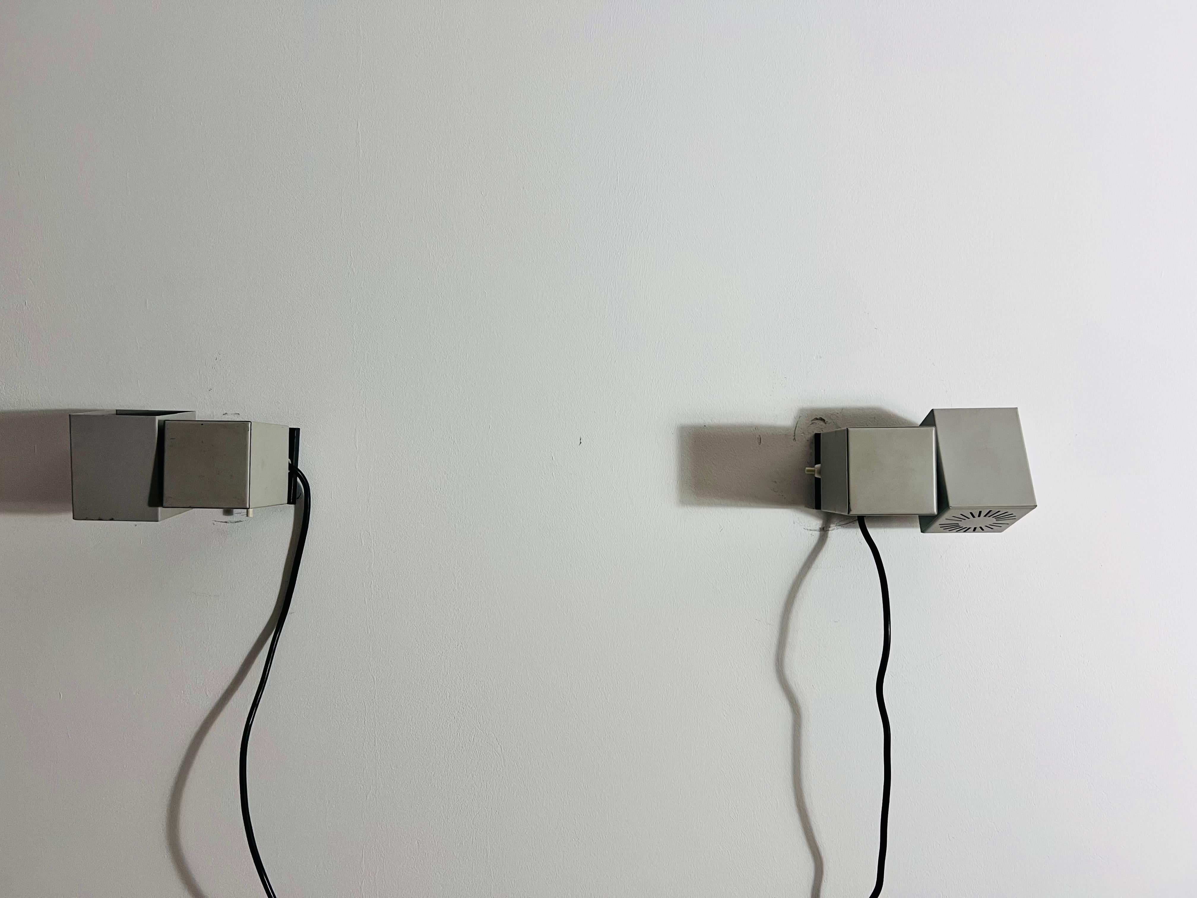 Un par de apliques vintage de Kaiser Leuchten, fabricados en Alemania en la década de 1970. Estas llamativas lámparas son de metal y presentan un diseño minimalista y cúbico inspirado en el movimiento Bauhaus. Cada lámpara consta de dos cubos