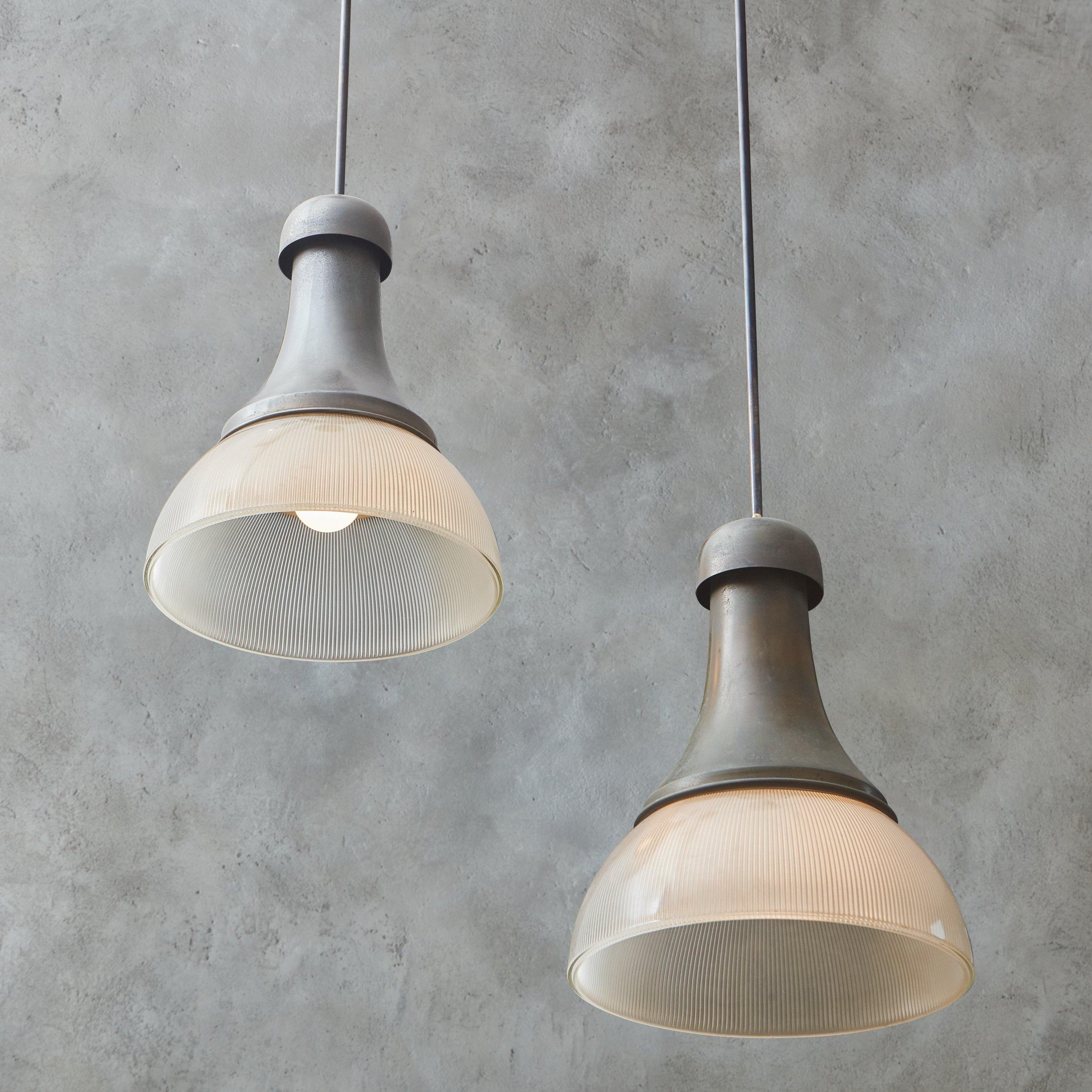 A pair of 1960s Italian pendant lights in the style of Sergio Mazza. These fixtures were constructed with patinated metal and feature beautiful fluted glass shades. They hang from 2’ metal stems and have new brass canopies with an antique finish.