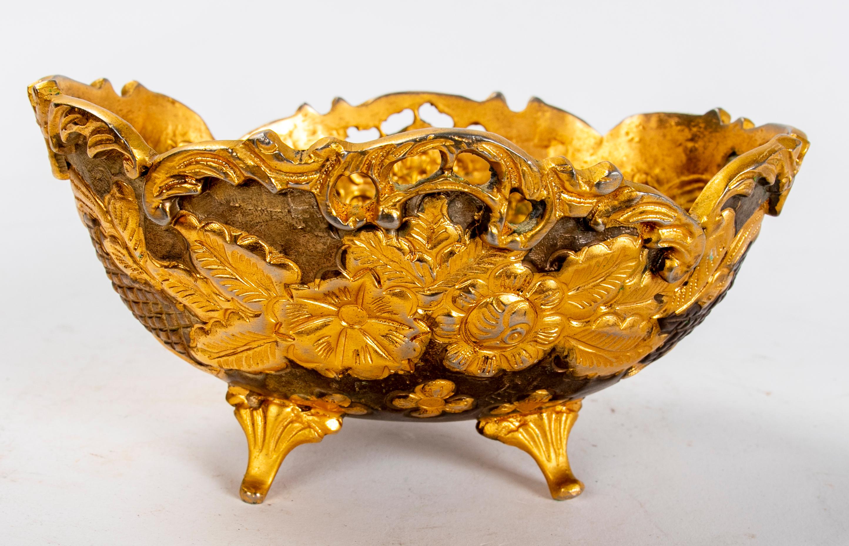 Ein Paar Metalltabletts in goldener Farbe mit Blumendekor.