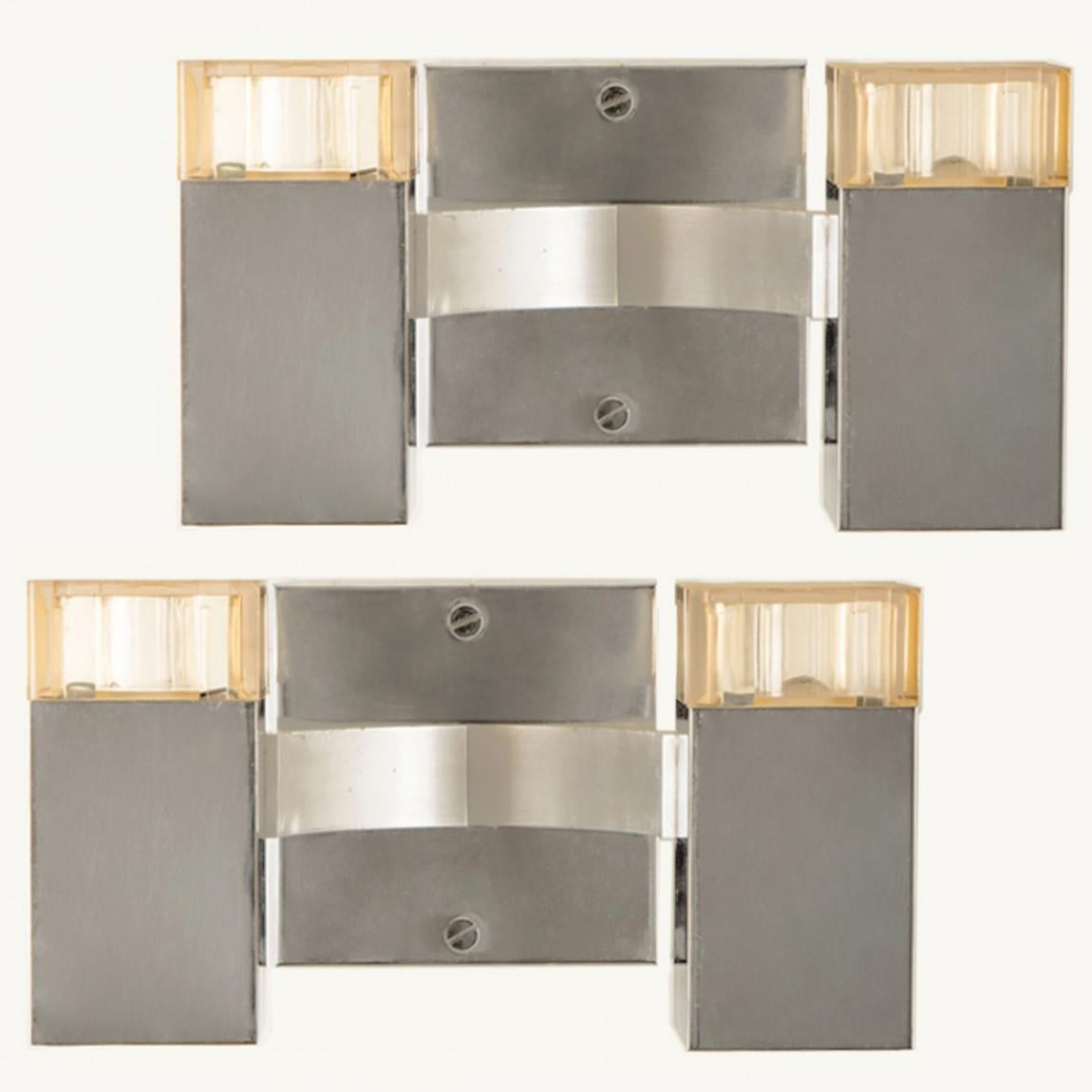 A pair of geometric wall fixtures, designed by Gaetano Sciolari in Italy in the 1960s.
They are composed of two rectangular tubes with a chrome finish. The light is also rectangular shaped.
Because of the highly polished surface, the lamp creates