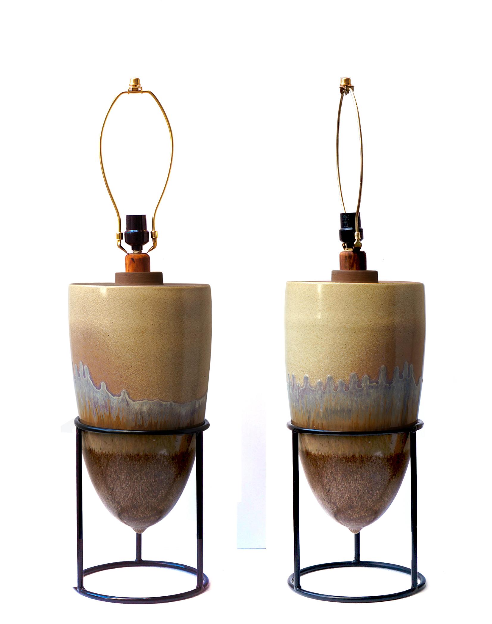 The midcentury period belongs to this spectacular pair of lamps created in ceramics suspended in a steel structure. Ceramic glazed in earth tones, with a small application of wood.
The pair of lamps is sold without a lampshade, for an extra cost we