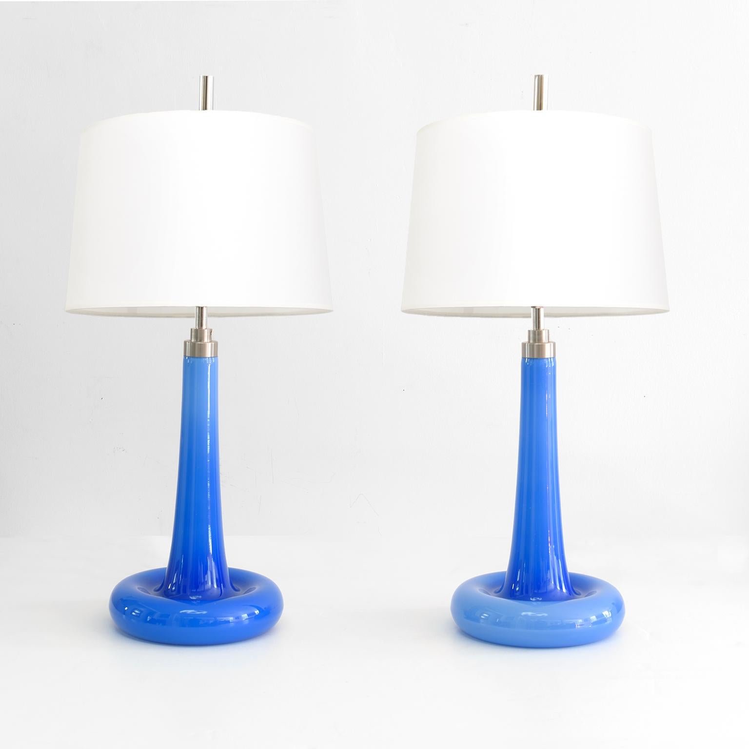 Pair of Michael Bang designed blue glass table lamps with an annular shaped bases and soft cone shaped bodies. The glass is capped with brushed metal hardware and a single 3-way standard base socket and matching harp. Newly rewired for use in the