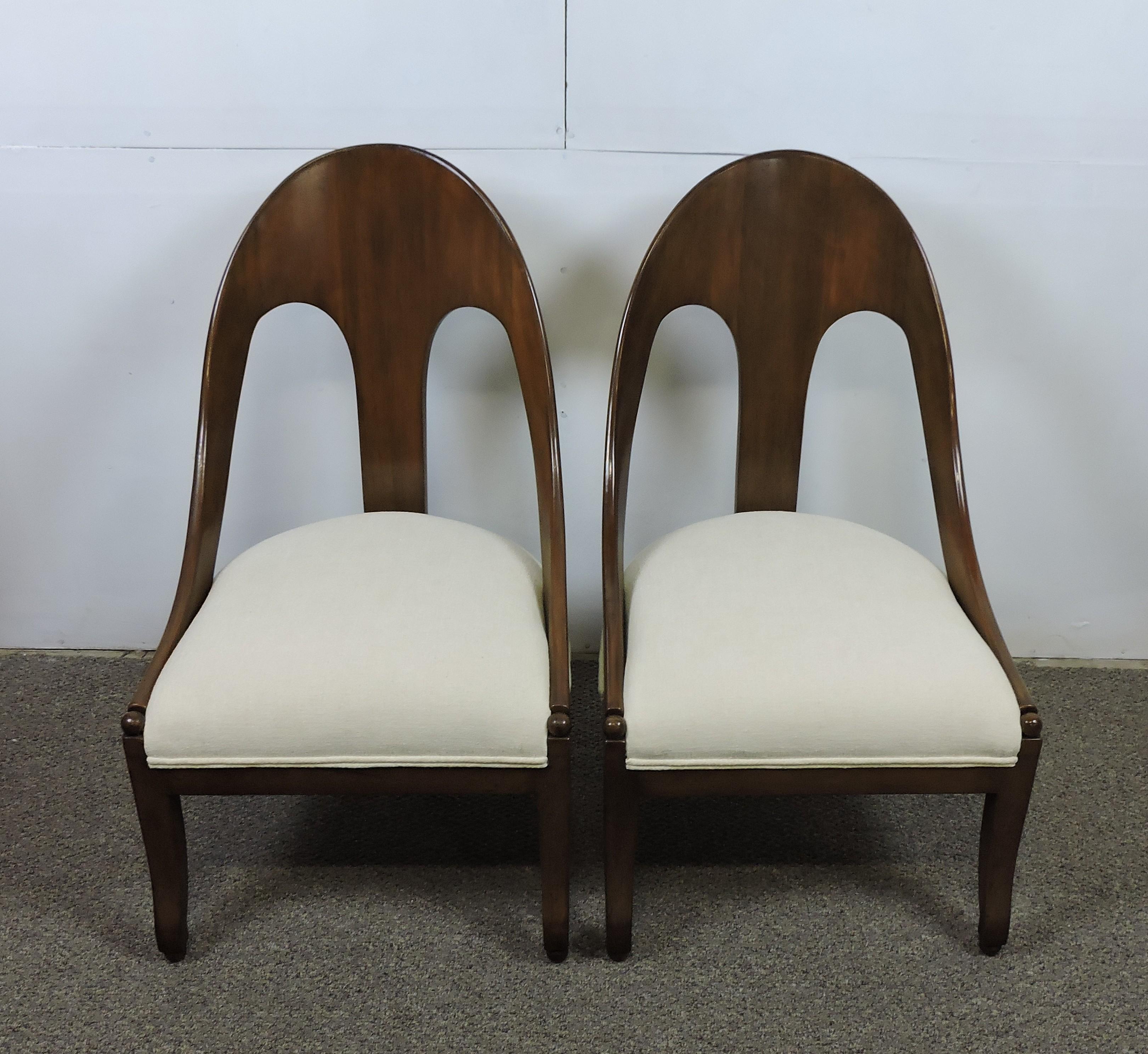 Elegant and graceful pair of neoclassical slipper lounge chairs designed by Michael Taylor and manufactured by Baker Furniture Company. These chairs are made of solid mahogany and are newly re-upholstered in an off-white chenille fabric.
