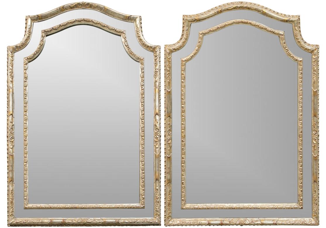 Pair of wall mirrors with arched crown and segmented border flanked by carved egg/dart motifs and floral bands.
Designed by Michael Taylor for Panache. The mirror glass and frame with intentional aged speckling and a wooden back.

Dimensions: 30.5