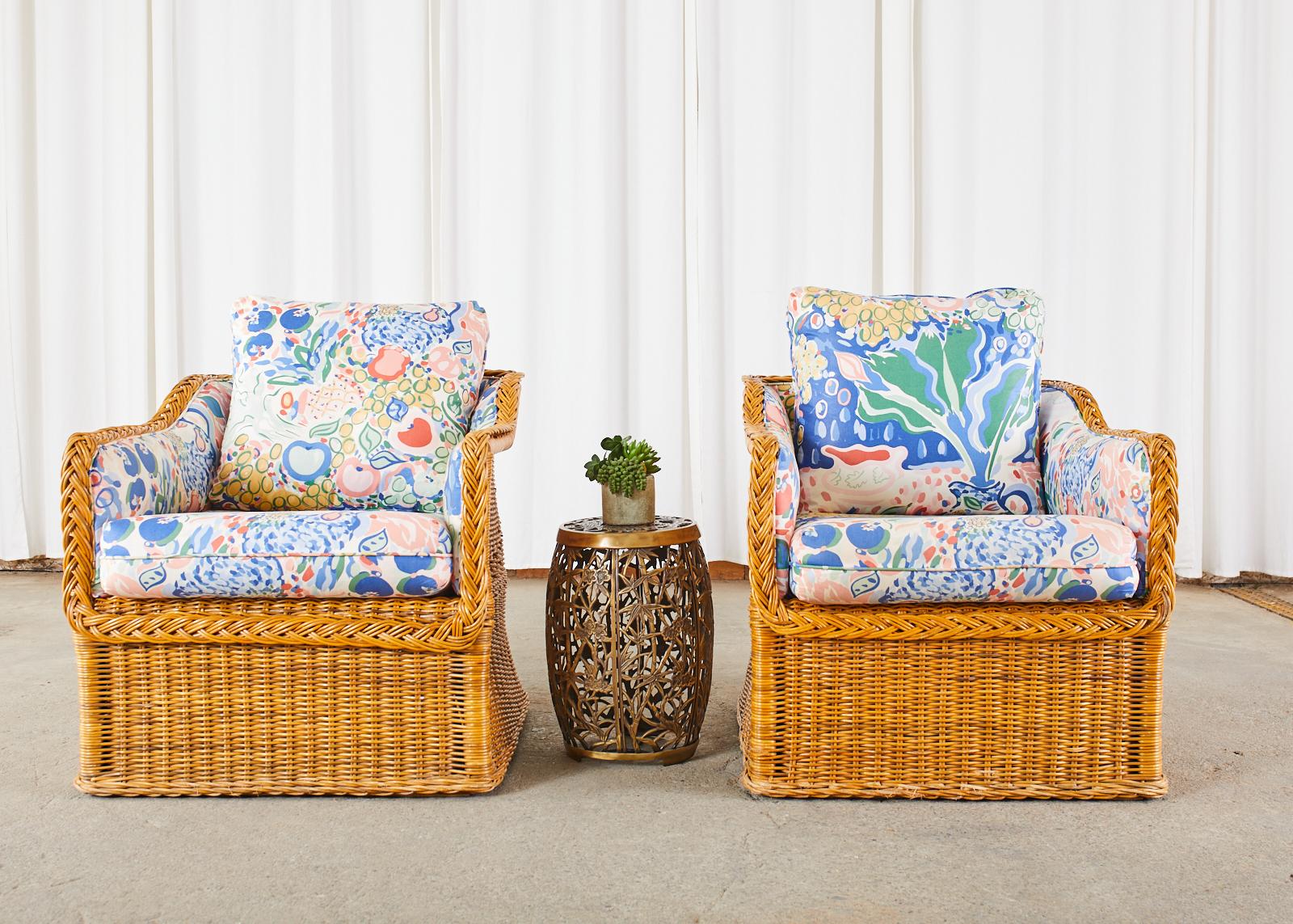 Stylish pair of cube shaped lounge chairs or club chairs crafted from wicker in the manner and style of Michael Taylor. Two chairs feature a rattan frame covered with woven wicker having a braided border along the edge. Made in the organic modern