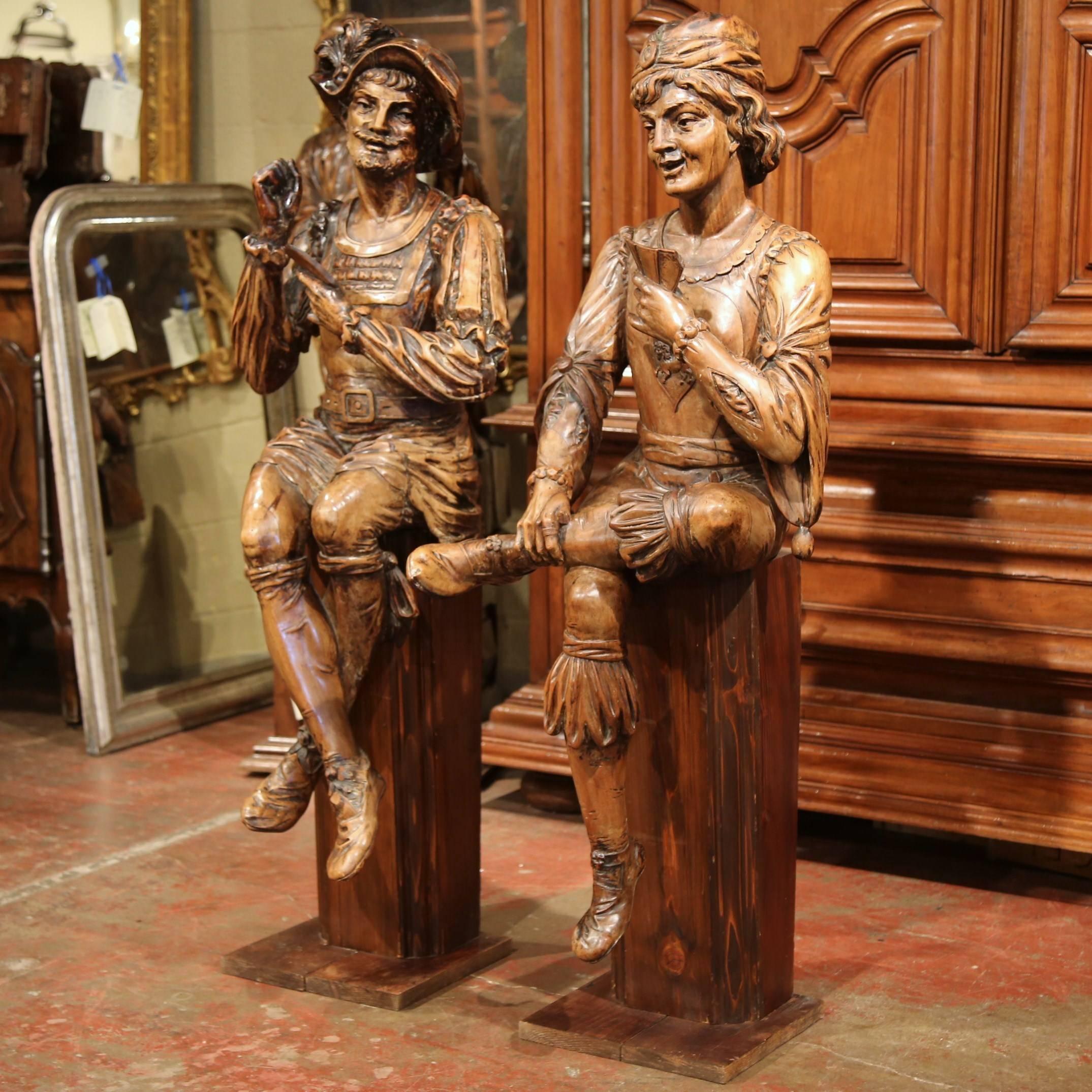 Bring new guests to your game room with this exceptional pair of large antique fruitwood figures! Crafted in Italy, circa 1760, each hand carved sculpture stands on a wooden base and features a young page playing cards. The hand carved sculptures