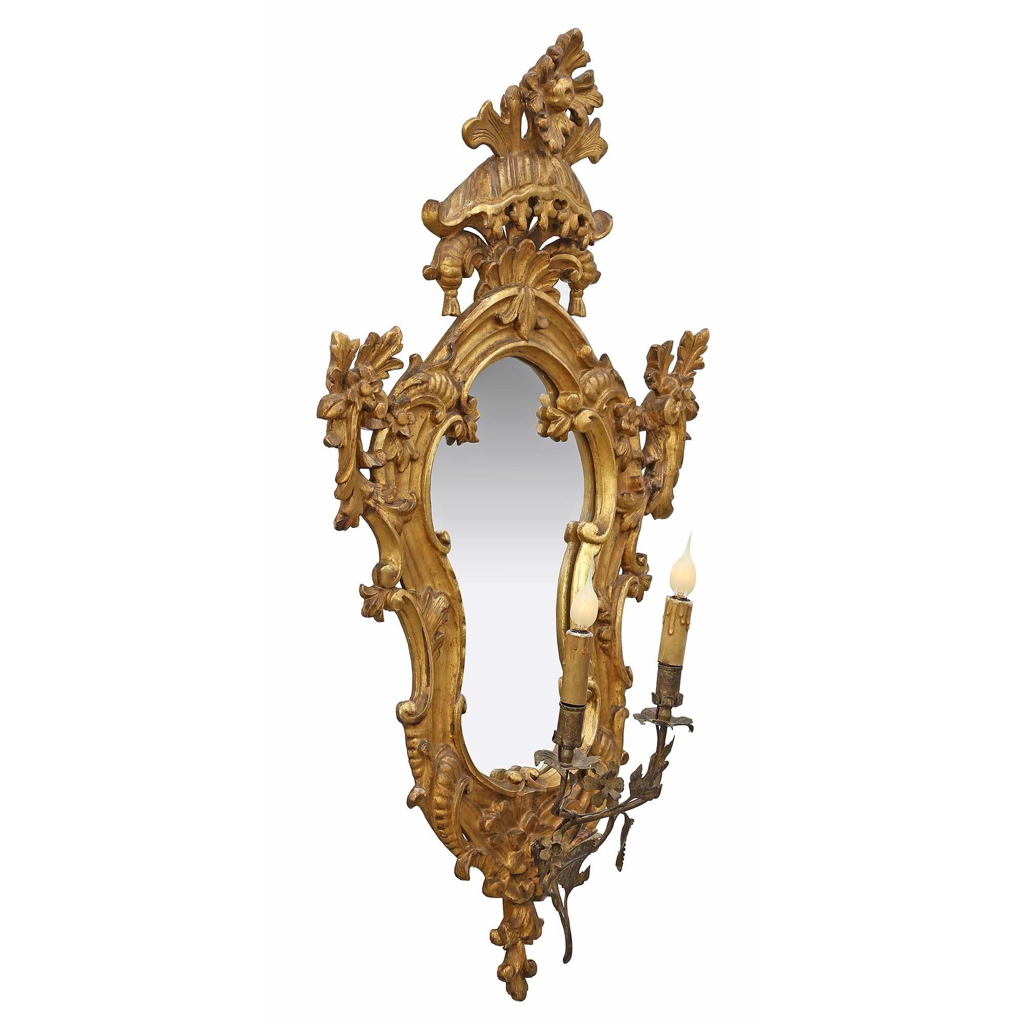 A sensational and high quality pair of mid 18th century Italian mirrored giltwood electrified sconces. The pair with all original gilt and mirror plates has a scrolled design with blossoming flowers. Above the bottom carved finial are the two