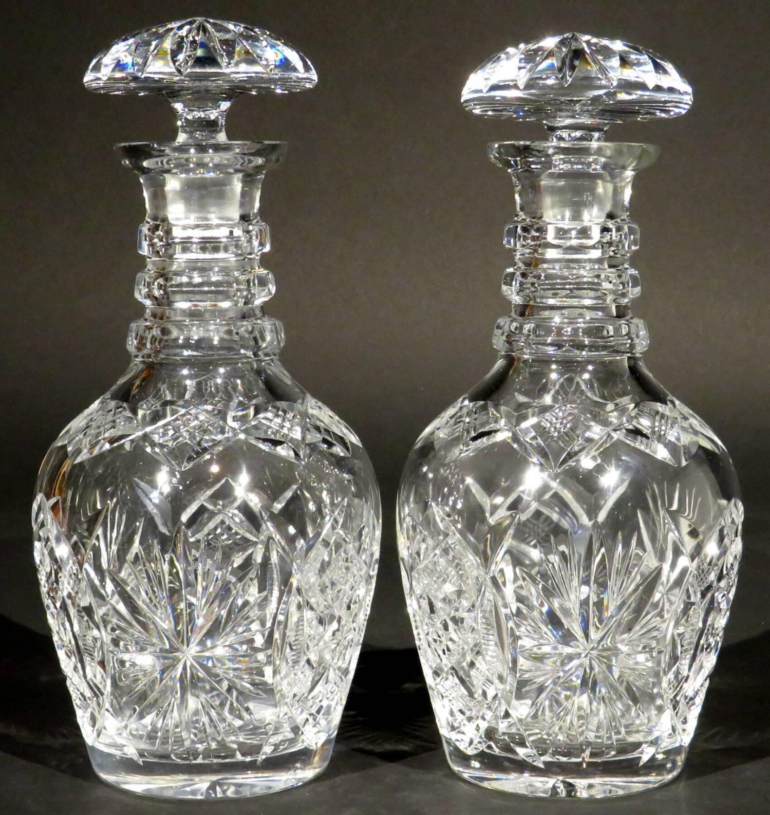 A handsome and robust pair of 19th century cut-glass decanters, both barrel shaped bodies showing deep cut repeating starburst & angular faceted motifs, rising to triple-ring necks fitted with star-cut mushroom stoppers, their undersides decorated