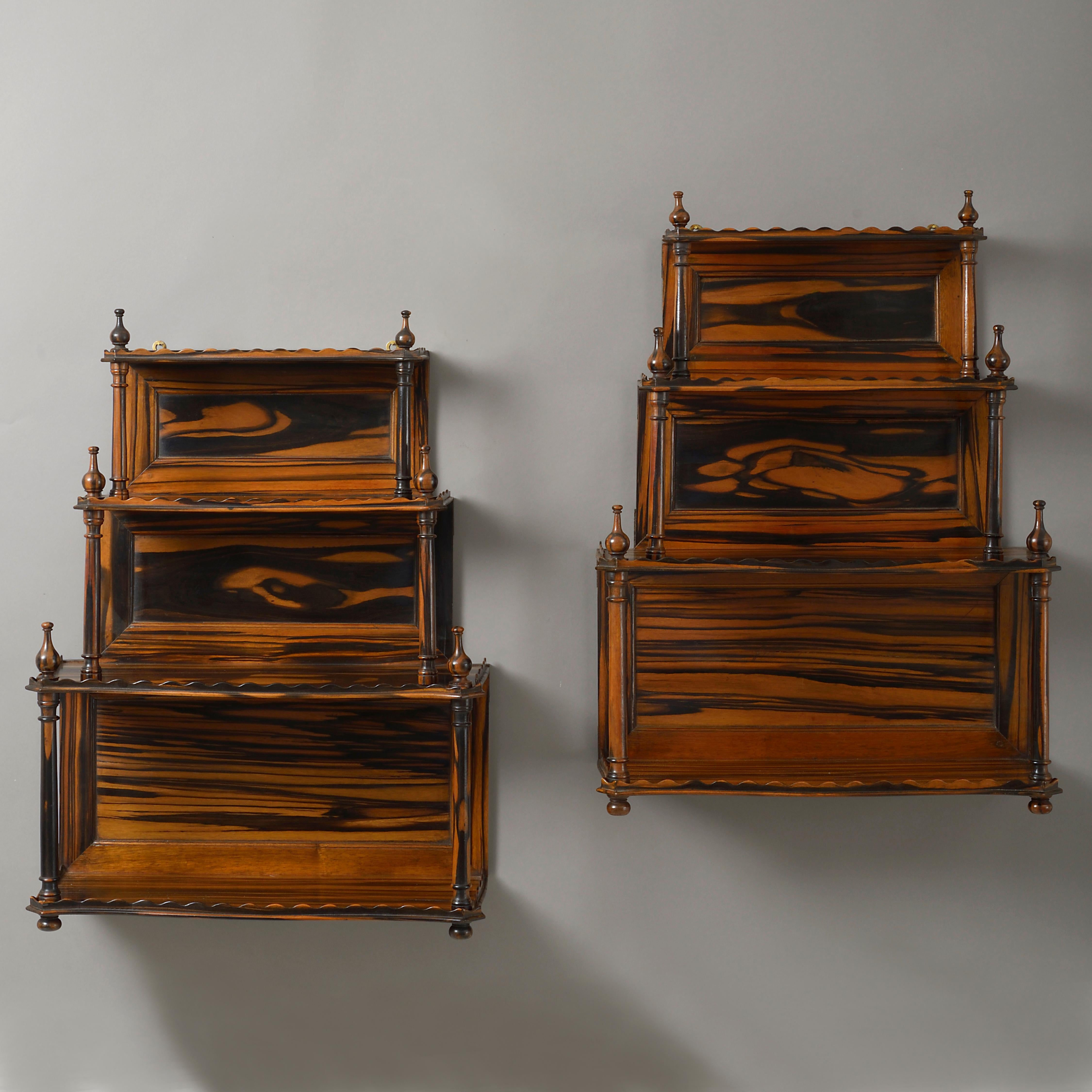 A pair of mid-19th century richly figured calamander wood hanging shelves, each having four tiers with scalloped galleries, supported by turned columns, all surmounted by finials, the backs with fielded panels.
