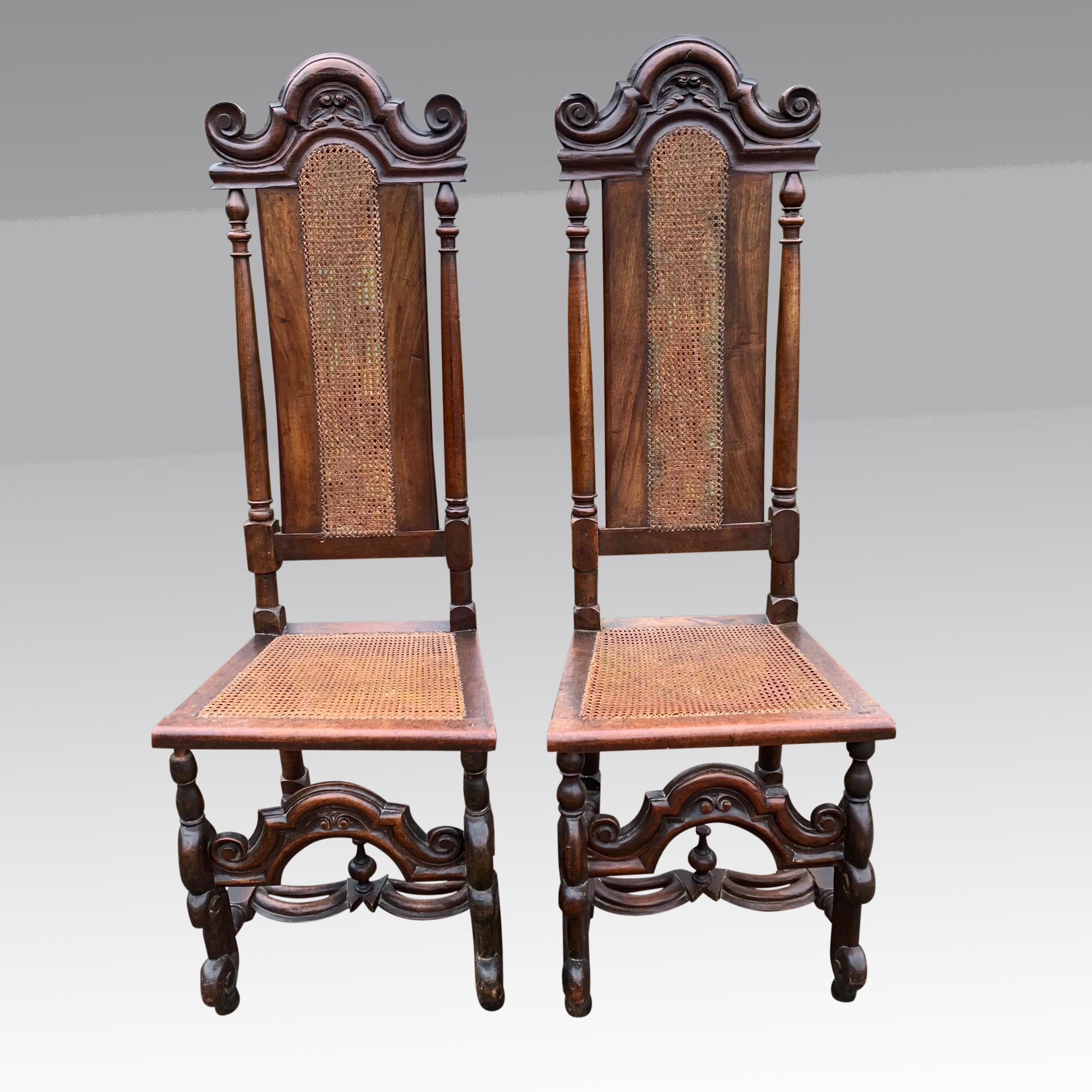 A good pair of mid 19th century Carolean style chairs in walnut with caned seats and backs. The high backs with decorative cresting rails carved with leaves and flowerheads, flanked by upward scrolling ends which sit above the central caned splats