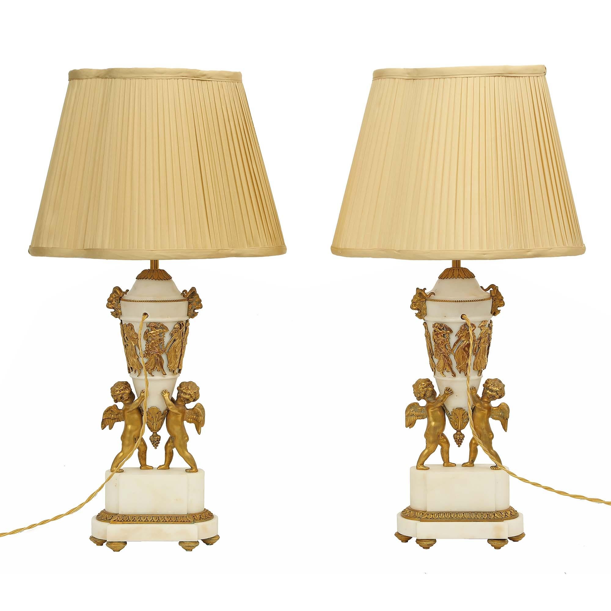 An exceptional pair of mid 19th century French Louis XVI st. white Carrara marble and ormolu urns mounted into lamps. The pair are raised by a marble base above topie shaped ormolu supports. The front of the base is decorated by an ormolu