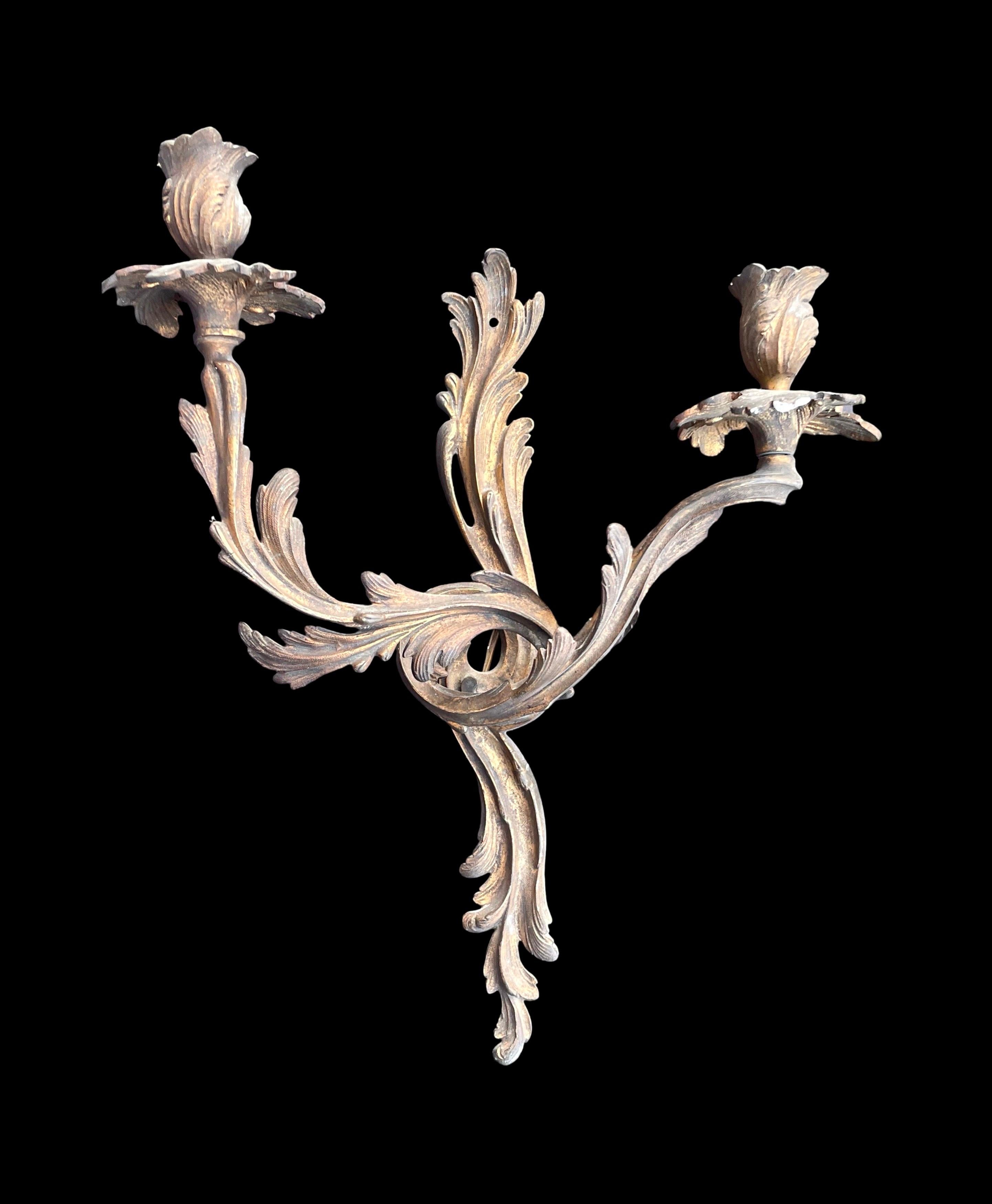 Un'affascinante coppia di applique francesi in bronzo in stile Luigi XV. Questo delizioso set è composto da appliques a due bracci, ognuna delle quali è ornata da portacandele che ricordano fiori sbocciati. 

Ispirate allo stile Rocaille, queste