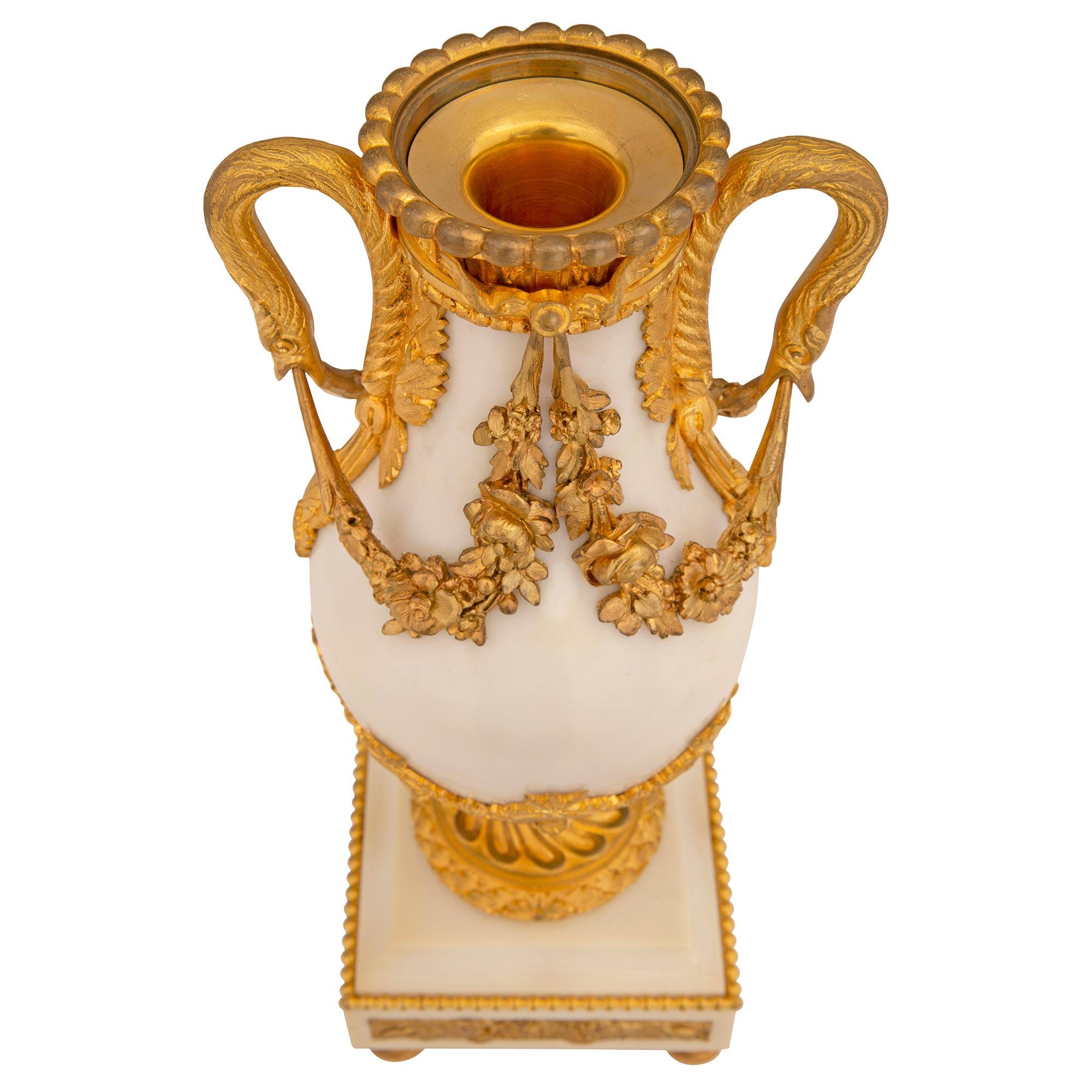 A superb pair of French 19th century Louis XVI st. white Carrara marble and ormolu cassolette urns. Each urn is raised by elegant topie shaped ormolu feet below the square white Carrara marble base decorated with a wrap around beaded band and
