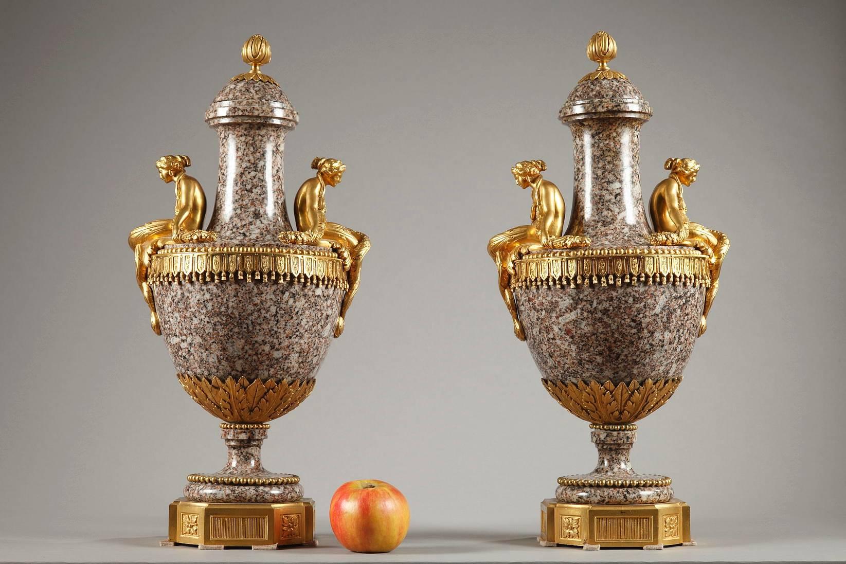 Paar Ziervasen aus Uraler Granit und vergoldeter Bronze im Louis-XVI-Stil. Junge Frauen in vergoldeter Bronze sitzen auf den Schultern der Granitvasen, die die Henkel bilden, den Rücken leicht nach vorne gebeugt unter dem Gewicht der Girlanden, die