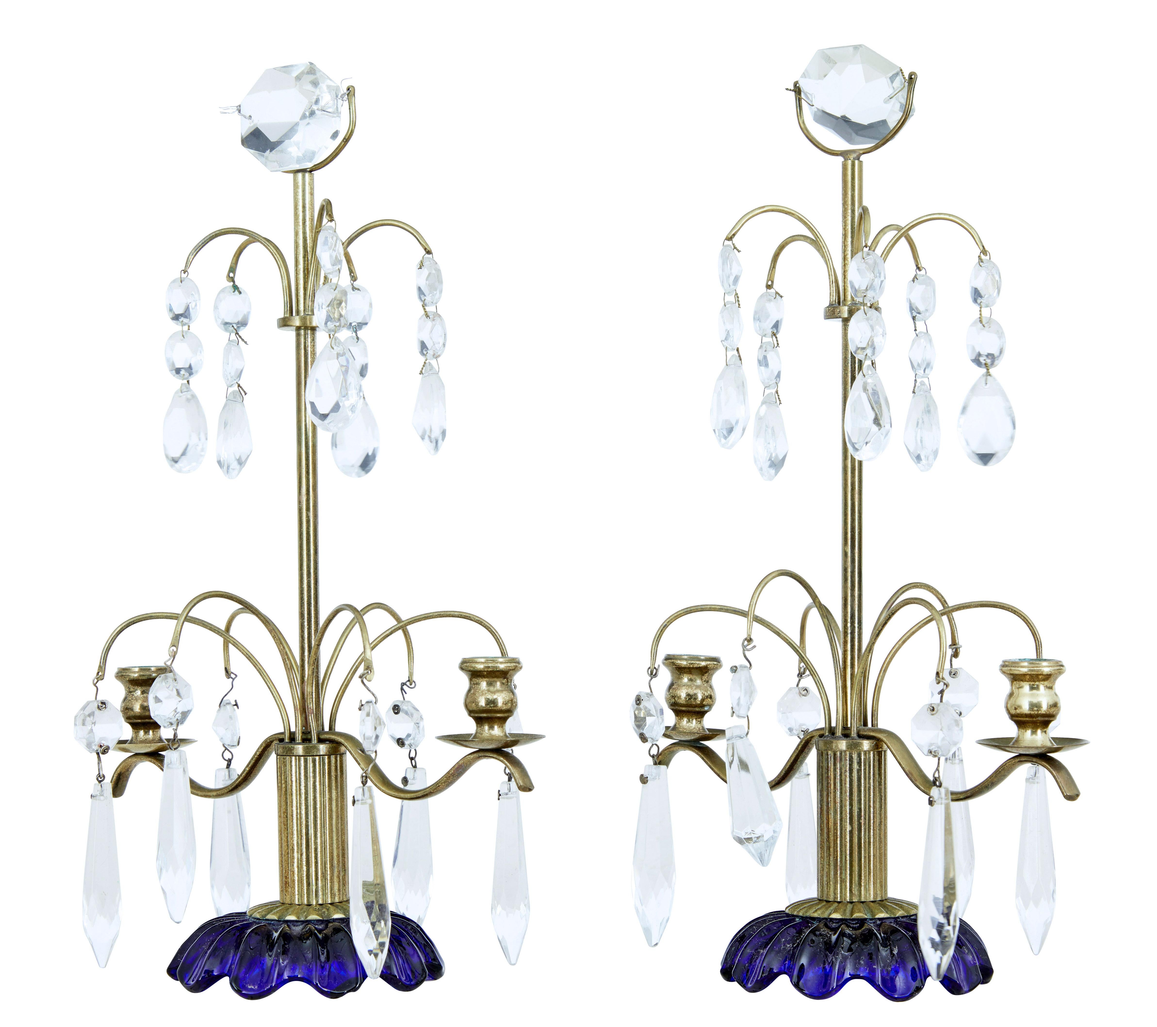 Pair of good quality cut glass candelabra circa 1960.

Brass frame with fluted column which links to the cobalt blue shaped base. Twin brass holders for small candles. Adorned with cut glass droplets.

1 replaced droplet which is smaller than