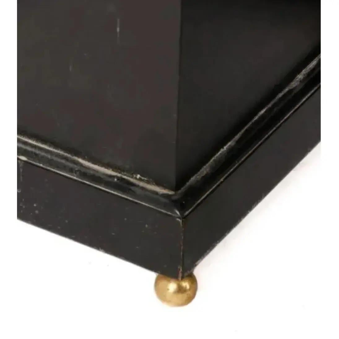 American, 20th century. Pair of ornamental black plant or urn stands in the style of Maison Jansen. These unmarked stands feature square, tapering bodies with brass lion's head and ring handles on each side. Standing at approximately 25