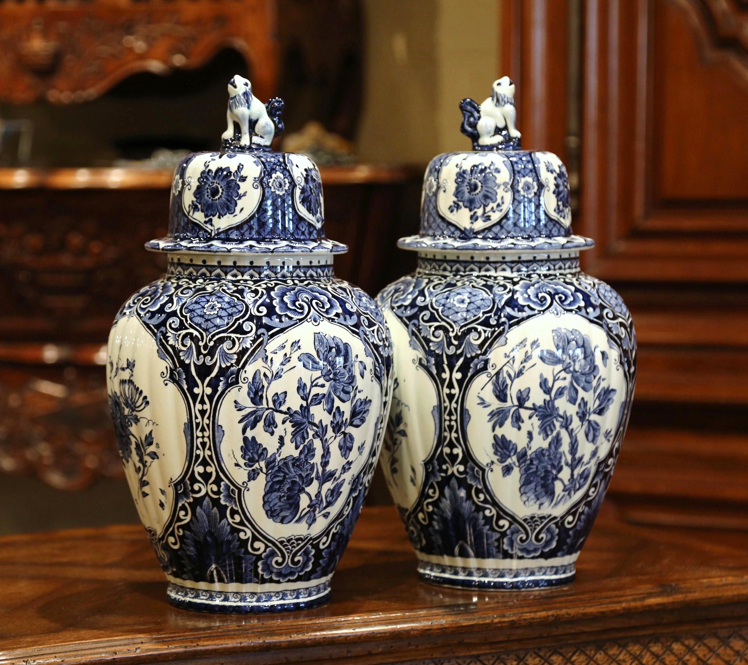Place this large and elegant pair of vintage ceramic ginger jars on a mantel or a buffet. Created in Holland circa 1950, the Classic faience potiches feature hand painted medallions with traditional Dutch flowers and foliage. The signature blue and