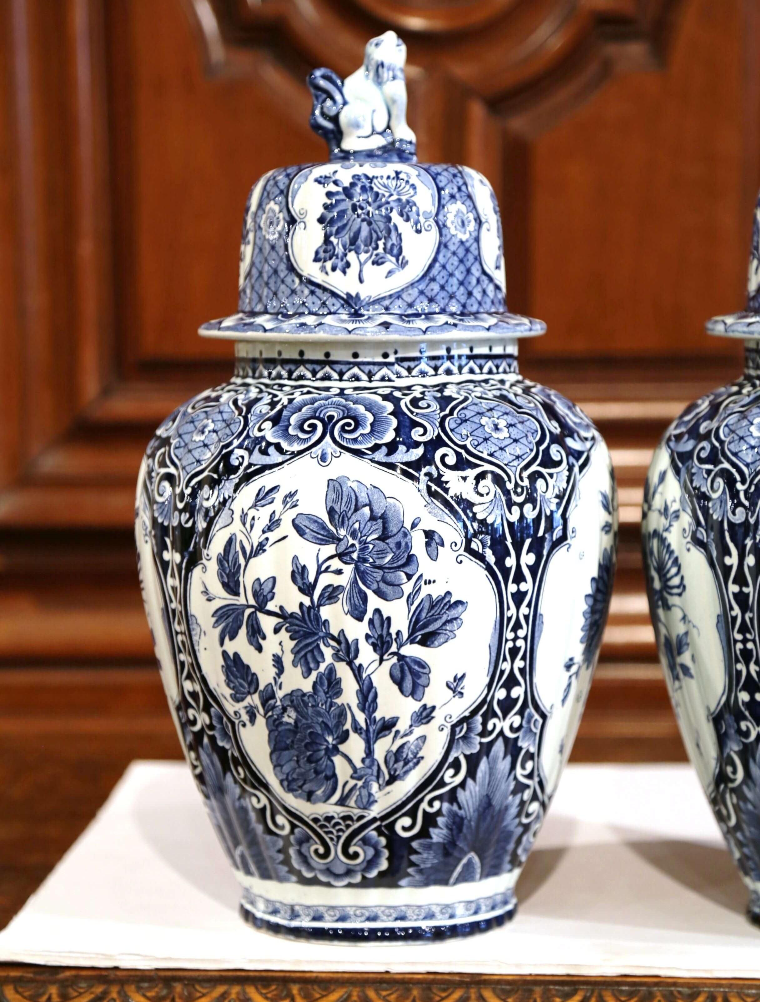 Place this large and elegant pair of vintage ceramic ginger jars on a mantel, created in Holland, circa 1960, the faience potiches feature hand painted medallions with Classic Dutch floral and foliage decor. Signed Delfts, the traditional blue and
