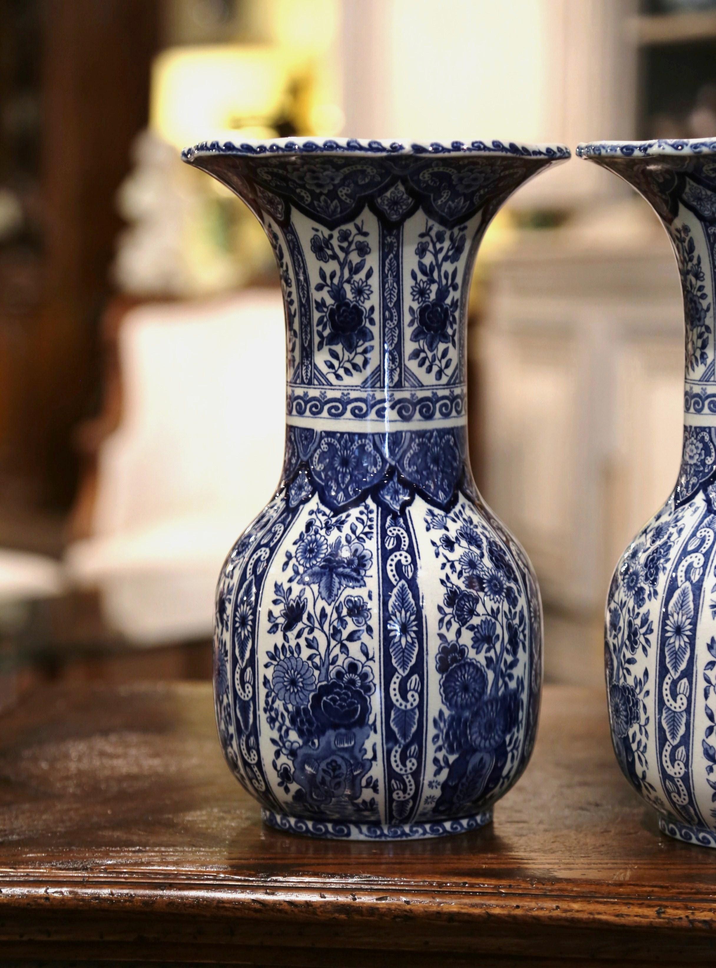 This elegant vintage pair of ceramic Delft vases was created in the Netherlands, circa 1940. Round in shape with a long neck and wide mouth, the faience flower vases feature traditional hand-painted floral decorations. They are stamped on the