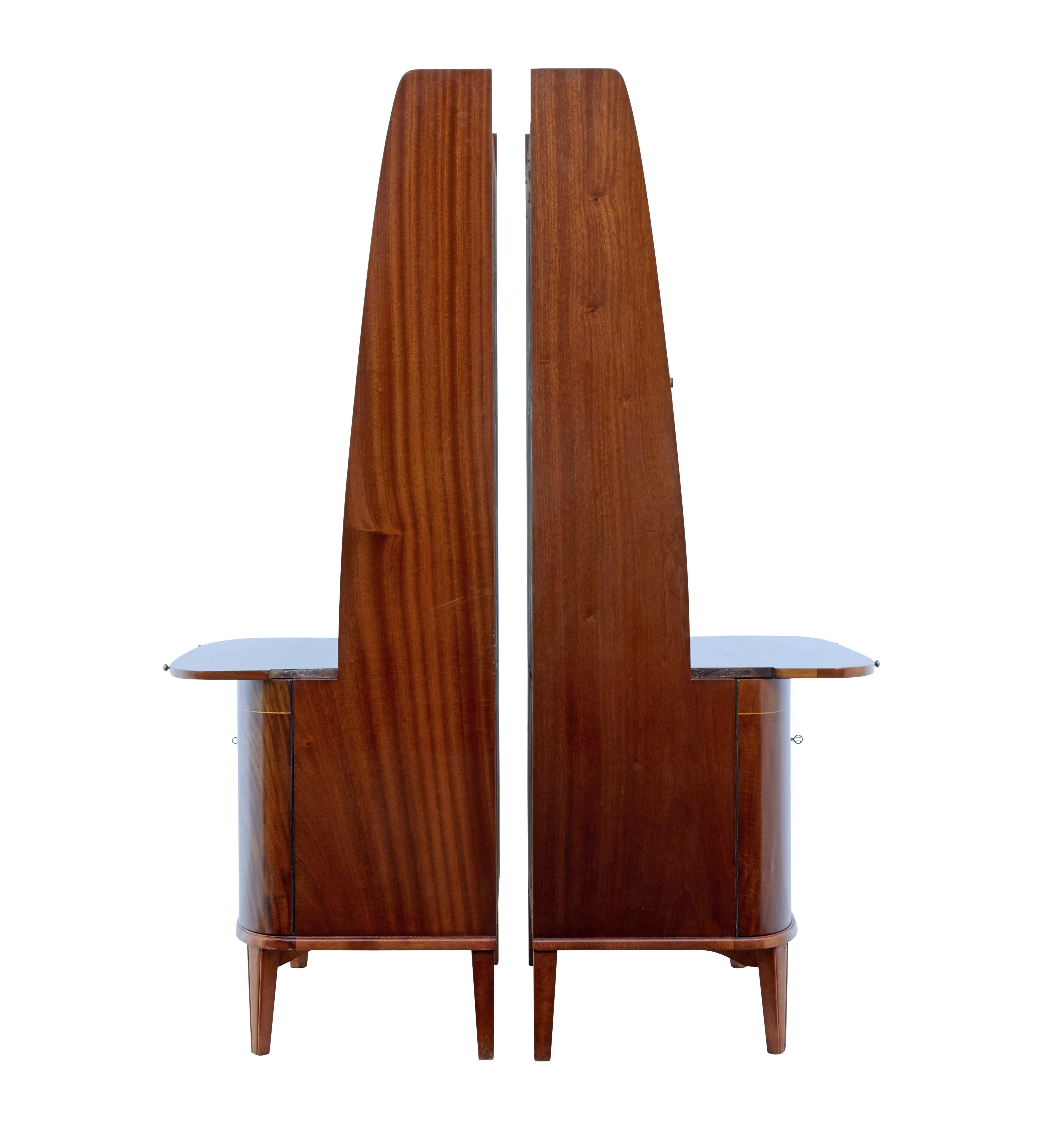 Pair of flame mahogany bookcase units circa 1950.

1 piece units, top section with 3 fixed shelves allowing 5 apertures for storage. Each surface fitted with a pullout / pull-out brushing slide. Below which a double door cupboard veneered with