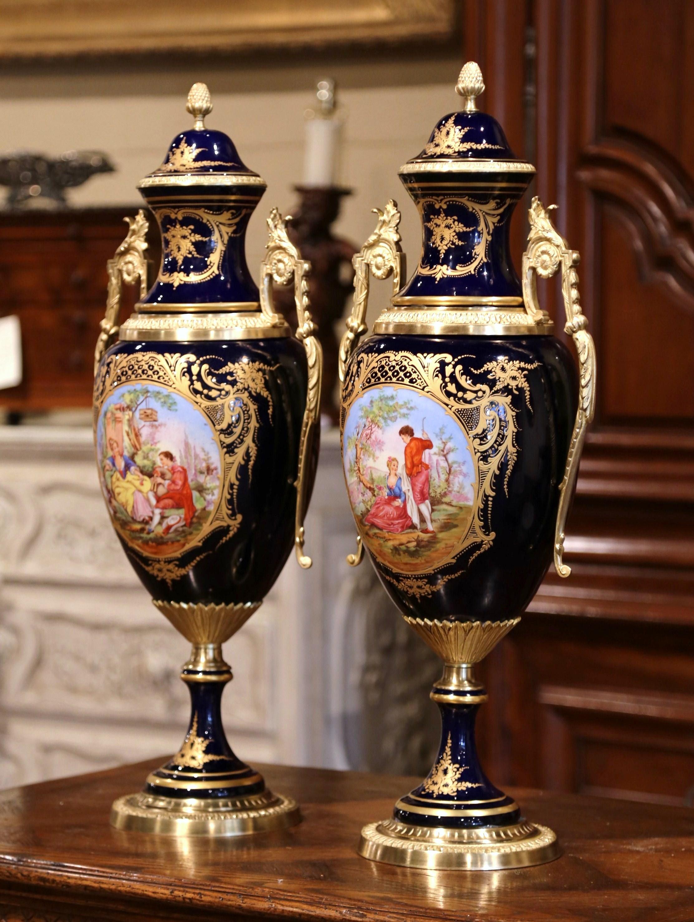 Decorate a mantel or a console with this important pair of porcelain and bronze Sèvres urns. Created near Paris, France, circa 1970, each impressive and elegant vase sits on a round bronze base. The vintage urns are decorated with hand painted