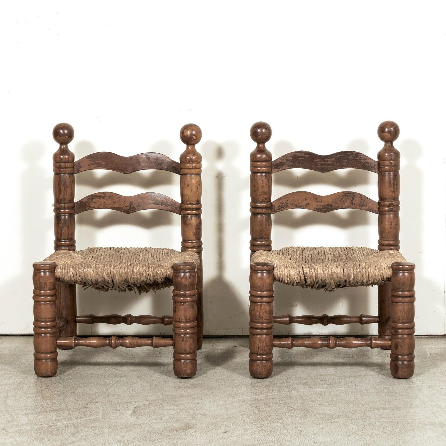 

A pair of mid-20th-century French Brutalist style chauffeuse, or fireplace chairs, by Charles Dudouyt, circa 1930s. These low, carved oak chairs combine rustic charm with refined craftsmanship, featuring ladder back frames with striking round