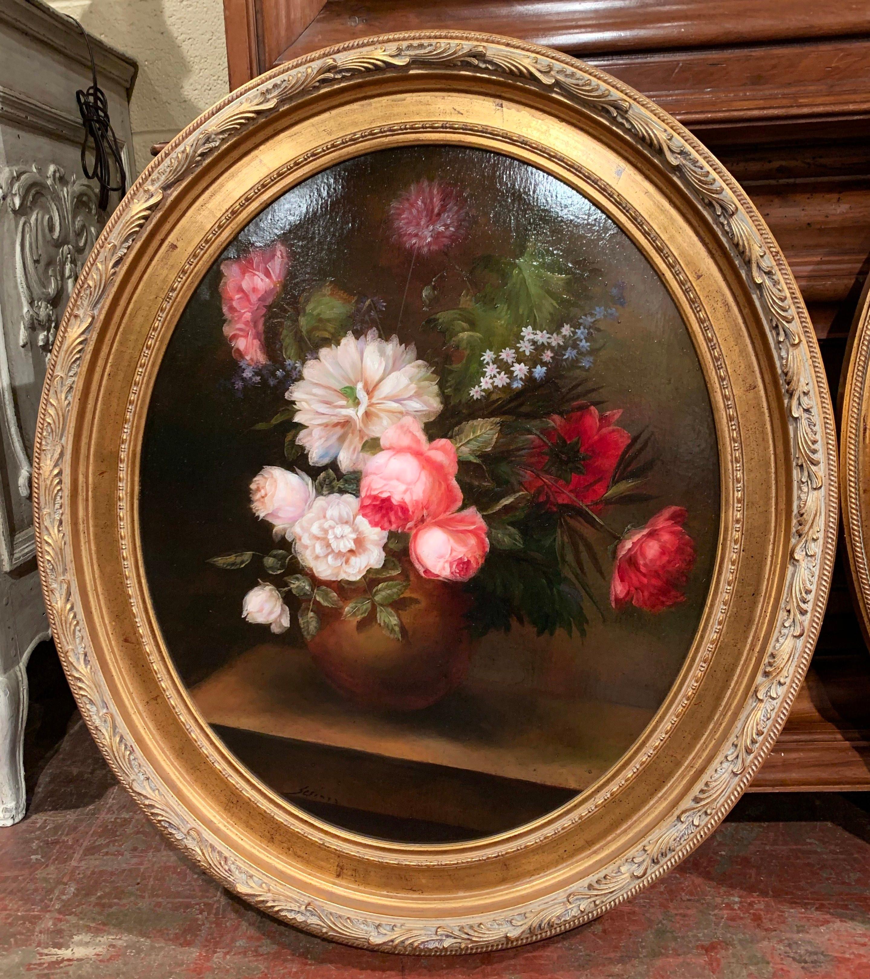Invite color into your home with this elegant pair of vintage oil on canvas paintings from France. Set in carved oval gilt frame, each canvas features colorful hand painted floral arrangements on a dark background. The traditional paintings with