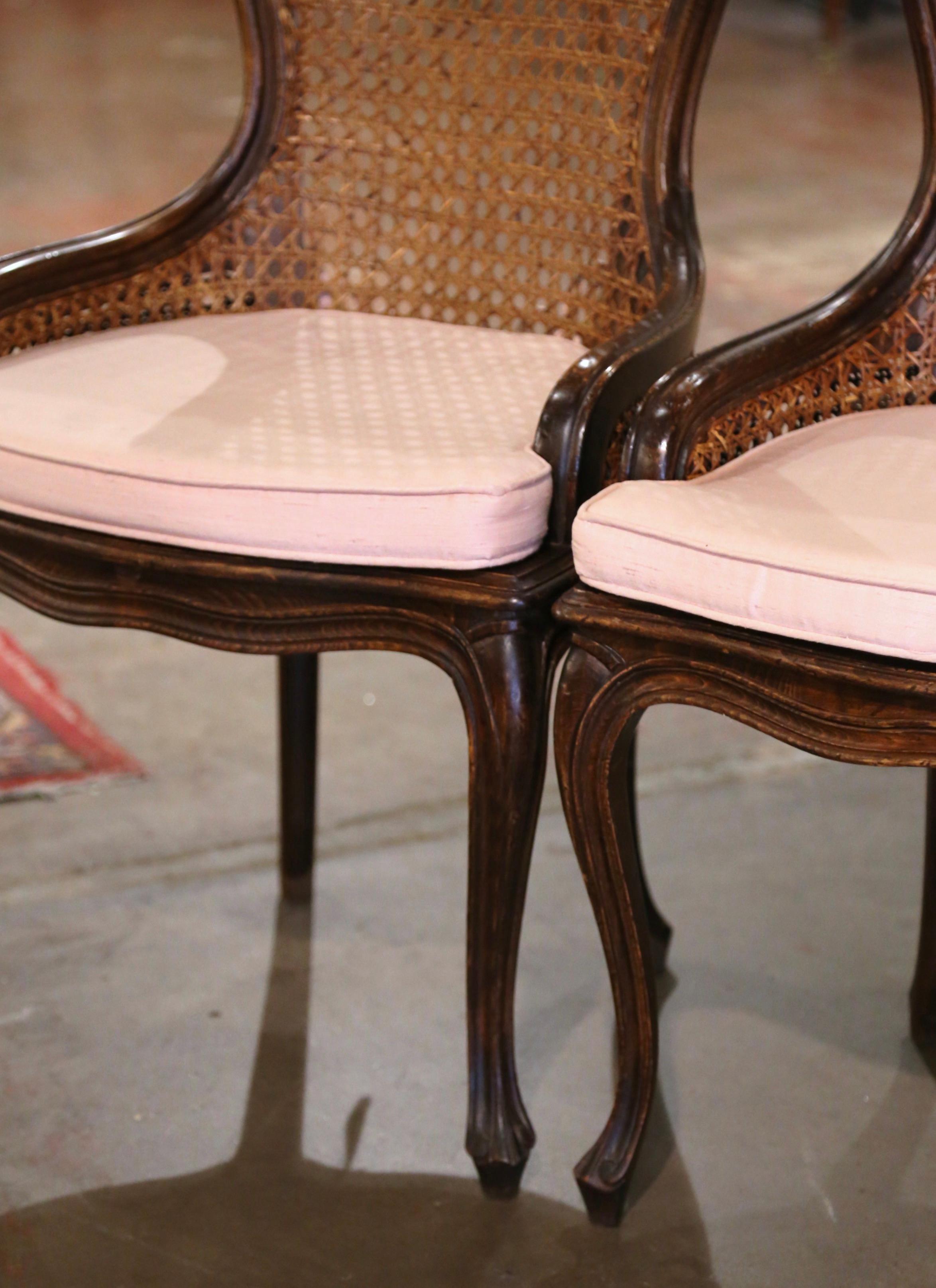 Crafted in France circa 1970 and nicely carved, each antique chair stands on cabriole legs over a bombe apron. The chair features a curved and arched back decorated with hand carved flowers and leaves at the pediment. Both seat and back are