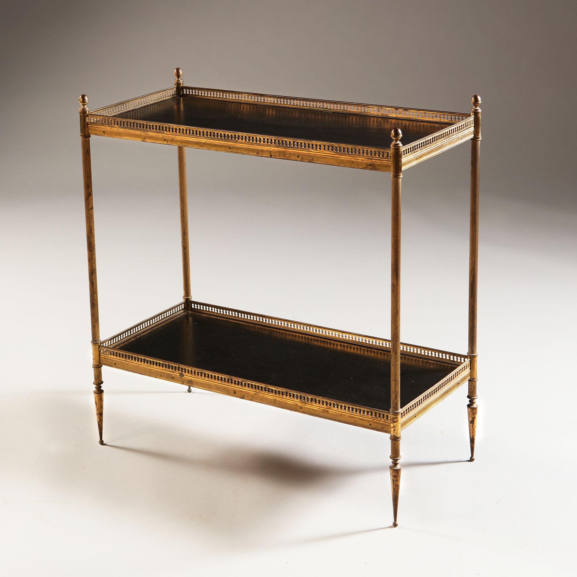 A pair of mid-20th century two tier etageres after Maison Bagues, with black leather tops with gilt tooling of a Greek key motif to the edges, with brass finials and pierced gallery to both levels, supported by fluted legs.