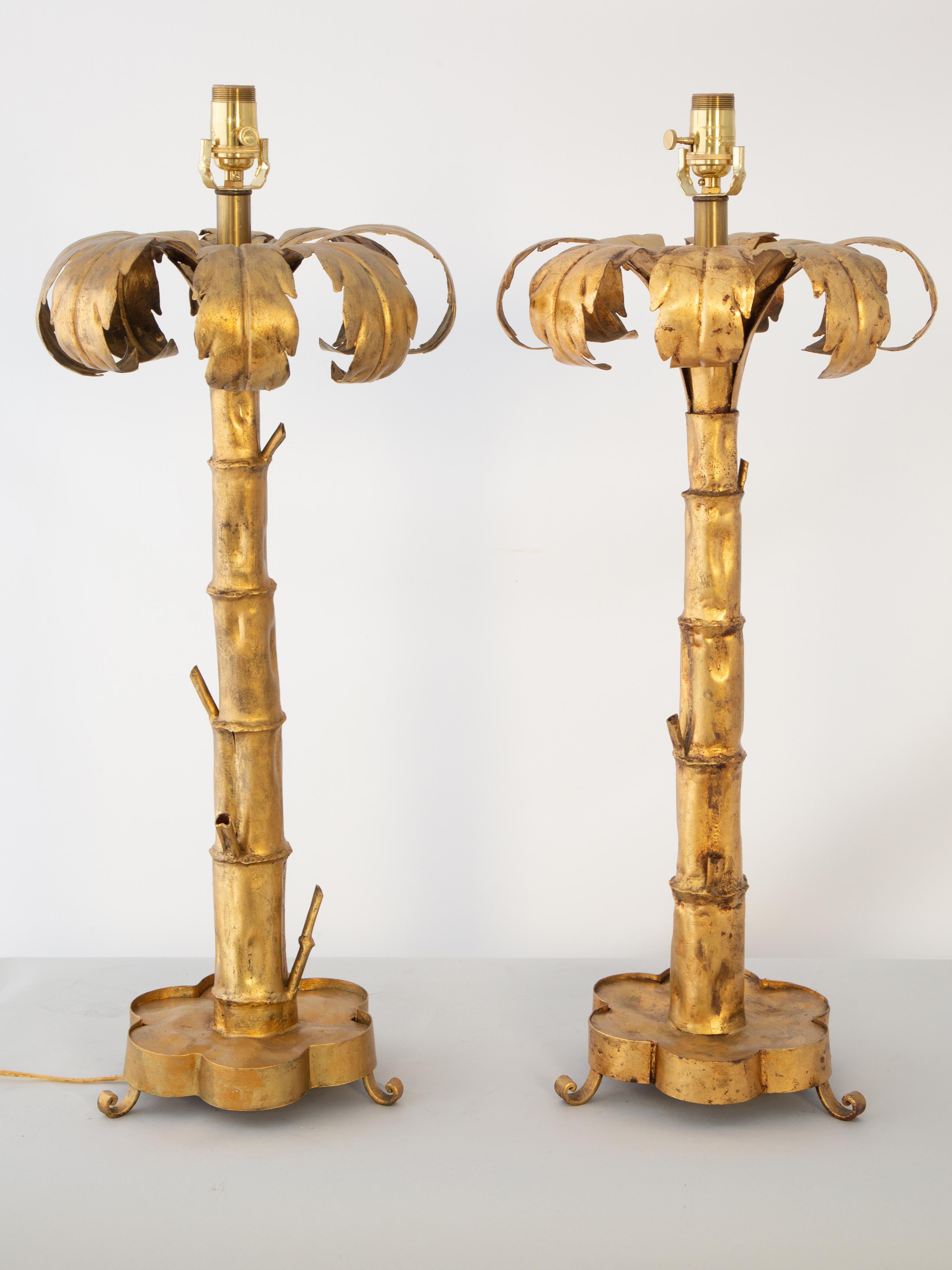 Pareja de lámparas de sobremesa, atribuidas a la Maison Jansen, con forma de palmera, de metal dorado. Las exageradas hojas de palmera coronan los troncos graduados, de estilo bambú, sobre una base de quatefoil, elevada sobre pies enroscados.  

ID
