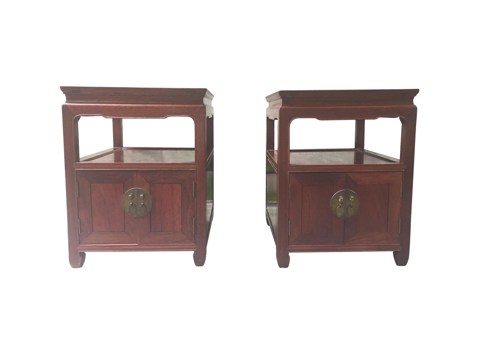 A pair of finely crafted, custom end tables or nightstands. Made in China, circa 1950. The tables are comprised of hongmu wood, a Hardy rosewood with a rich, warm tone. They are constructed with a single shelving unit and a two-door cabinet below