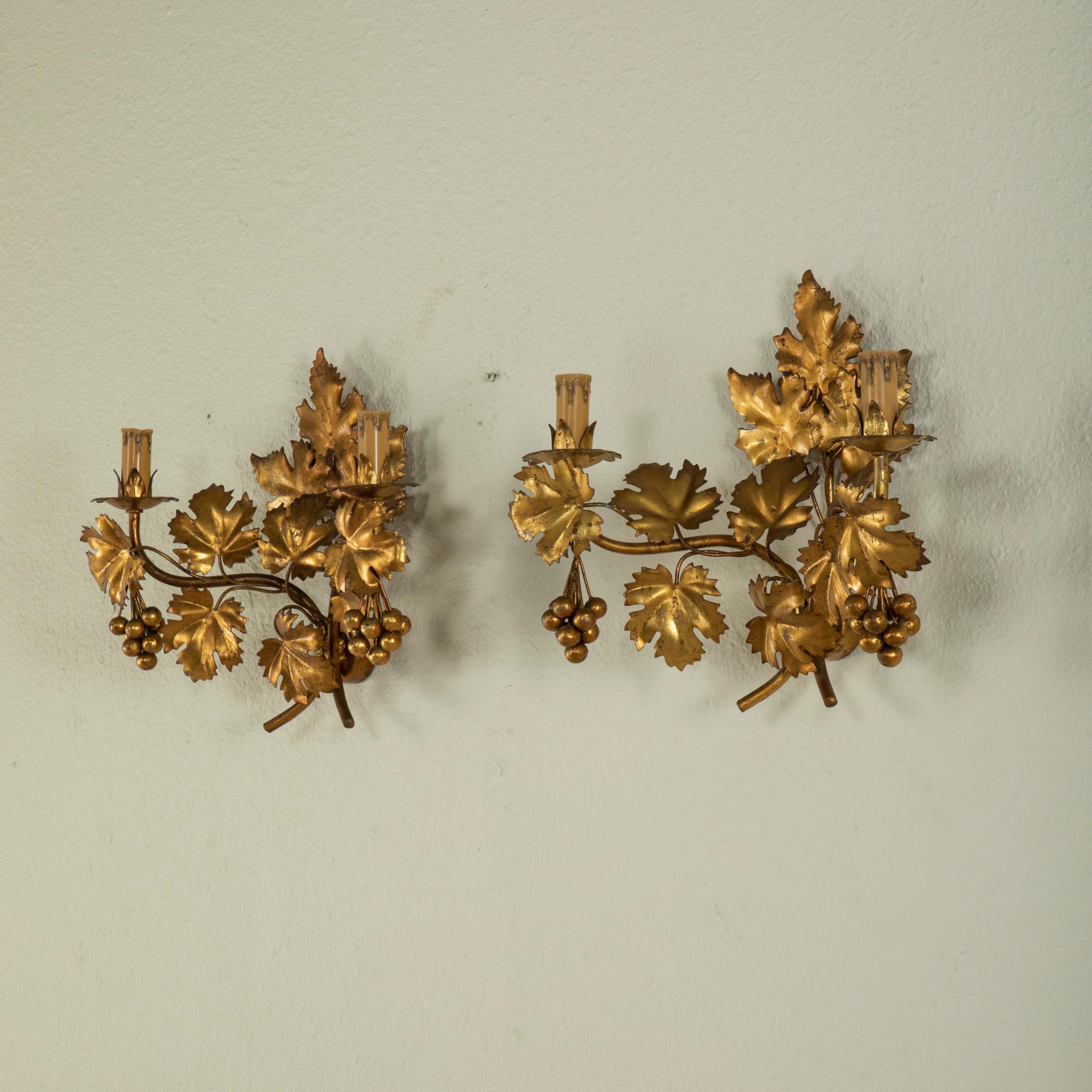 This pair of mid-century Italian gilt metal sconces features grape leaves that twist around the armatures. Bunches of grapes hang at each end of the sconces. At 14.5 inches in height, this fine pair makes a grand impact when flanking a mirror. These