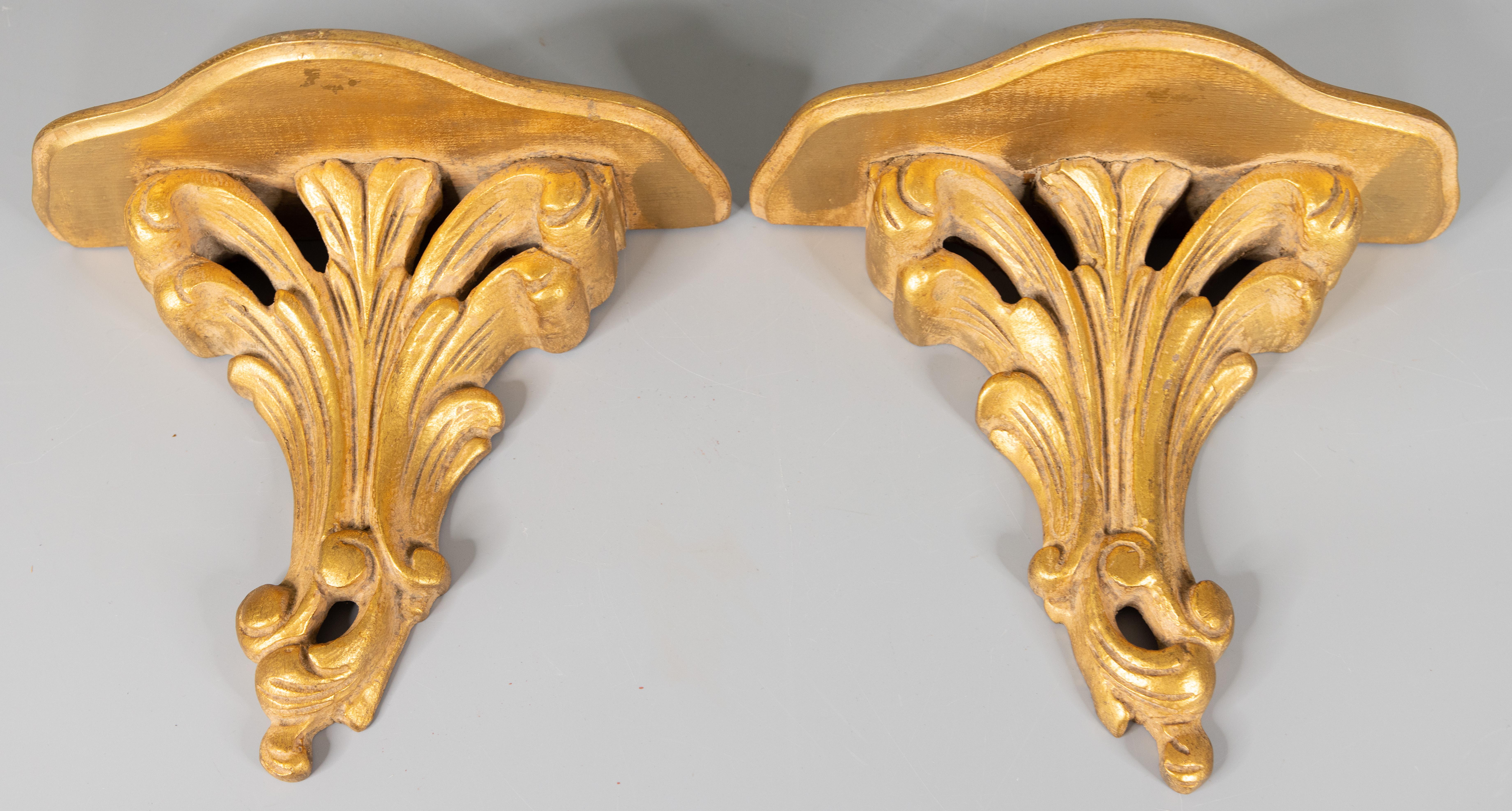 A lovely pair of vintage mid-century Italian gilded wood wall brackets shelves. These stunning brackets have hand carved scrolls in a beautiful gilt patina. They are perfect for displaying decorative collectibles or fabulous on their own.