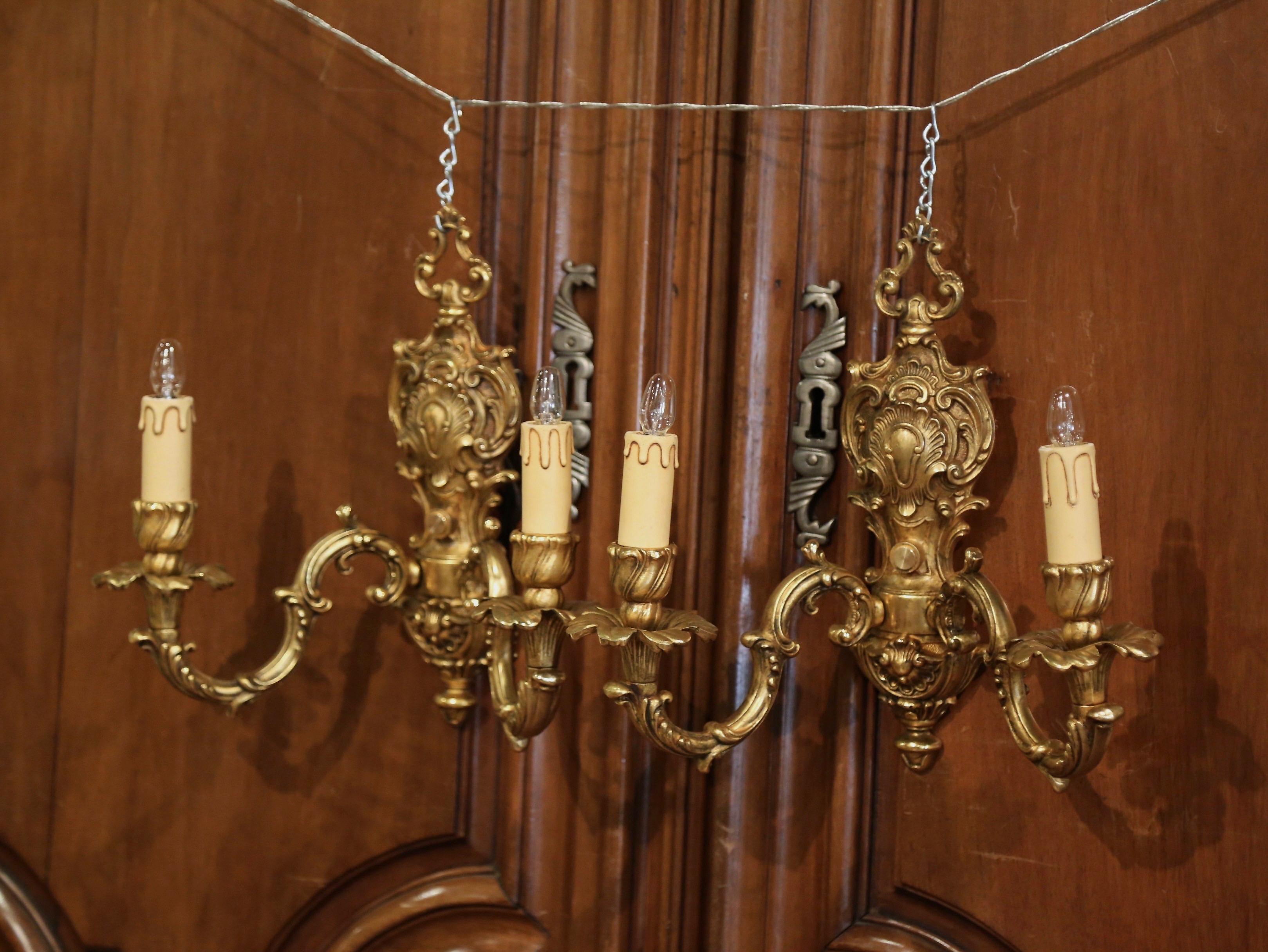 Decorate a powder room with this elegant pair of antique sconces; crafted in Italy, circa 1950 and made of brass, each ornate sconce with two-light features foliate, leaf, and shell motifs. The delicate, traditional light fixtures are in excellent