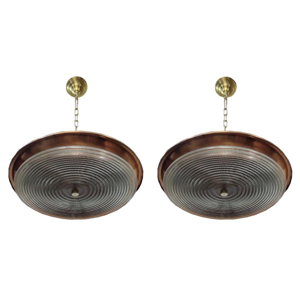 This is a fabulous pair of vintage pendant lights. It is a married combination of large copper shades from a decommissioned ship coupled with a large, prismatic Holophane lead crystal plate. Includes brass canopy and 4' of chain. Both date to the