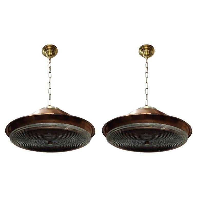 Il s'agit d'une fabuleuse paire de lampes suspendues vintage. Il s'agit d'une combinaison de grands abat-jour en cuivre provenant d'un navire désarmé et d'une grande plaque prismatique en cristal de plomb Holophane. Comprend un baldaquin en laiton