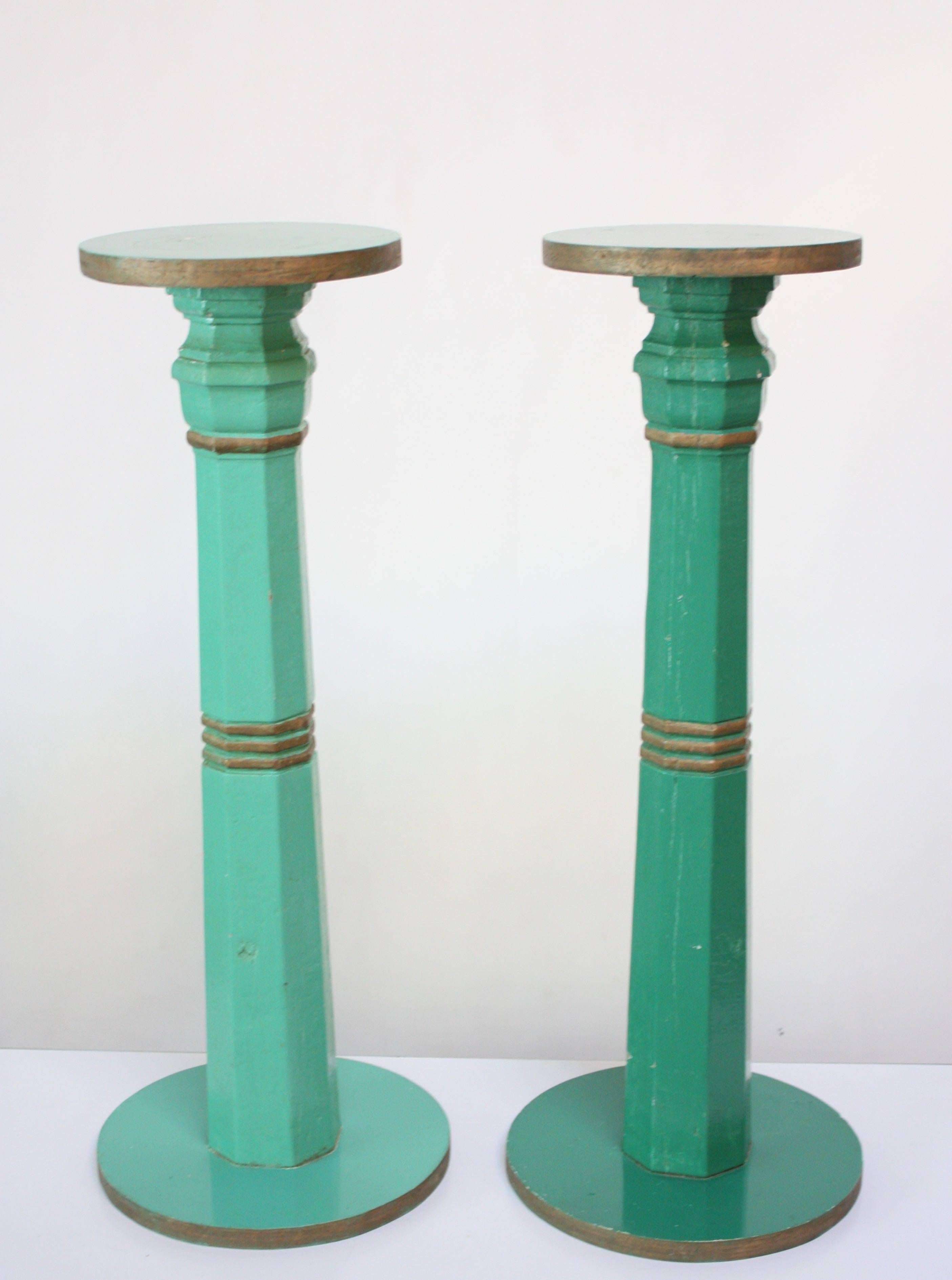 Pair of charming Primitive circular column pedestals in mint green with gold painted accents (one slightly darker than the other). Moderate surface wear commensurate with age and use as well as spots of paint loss throughout. 
Base diameter: