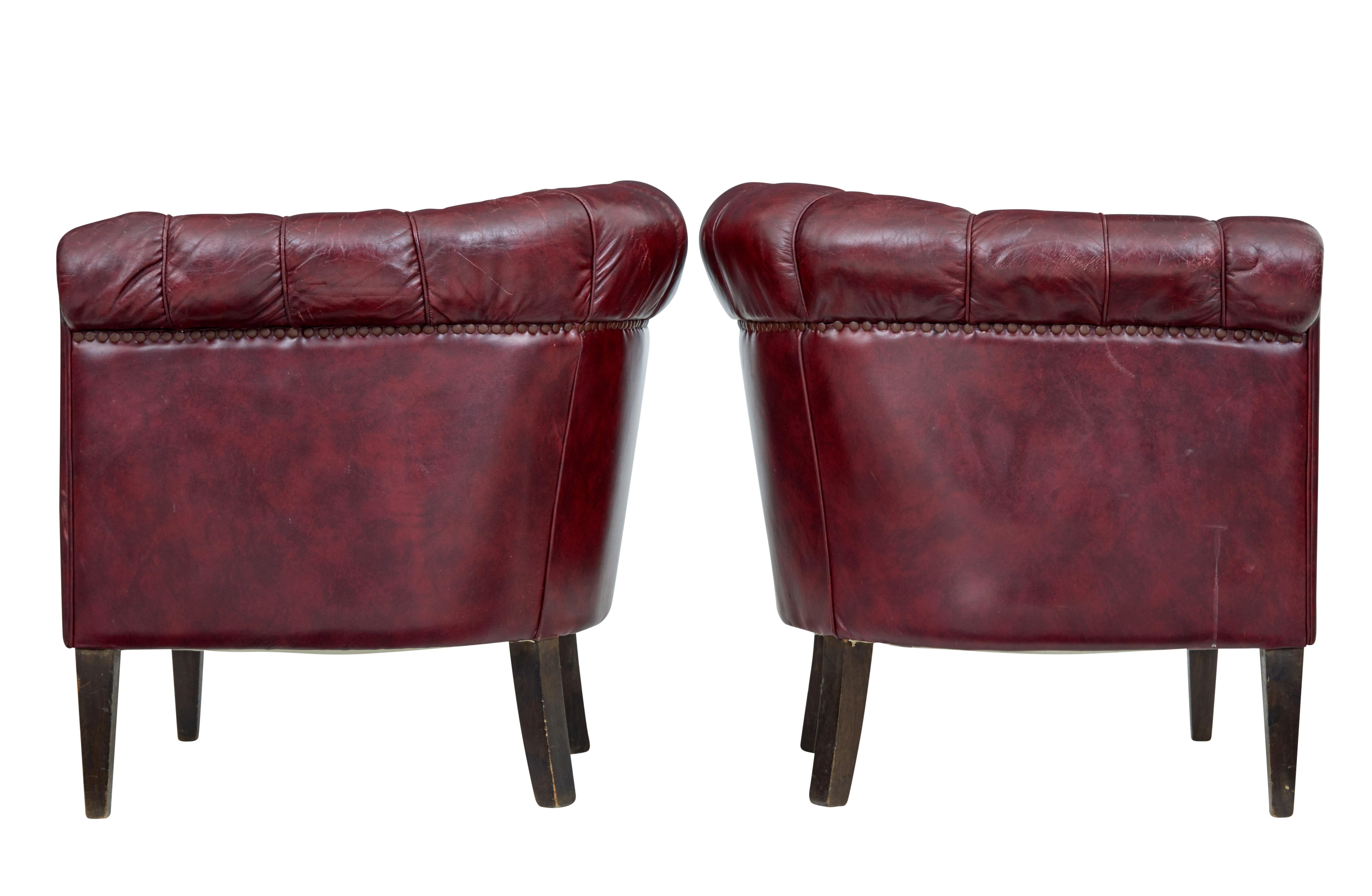 Good quality pair of leather armchairs, circa 1950.

Over stuffed arms and button back design make these a very comfortable pair of chairs. Deep red leather arranged with piping and studwork.

Leather in very good condition for age with very