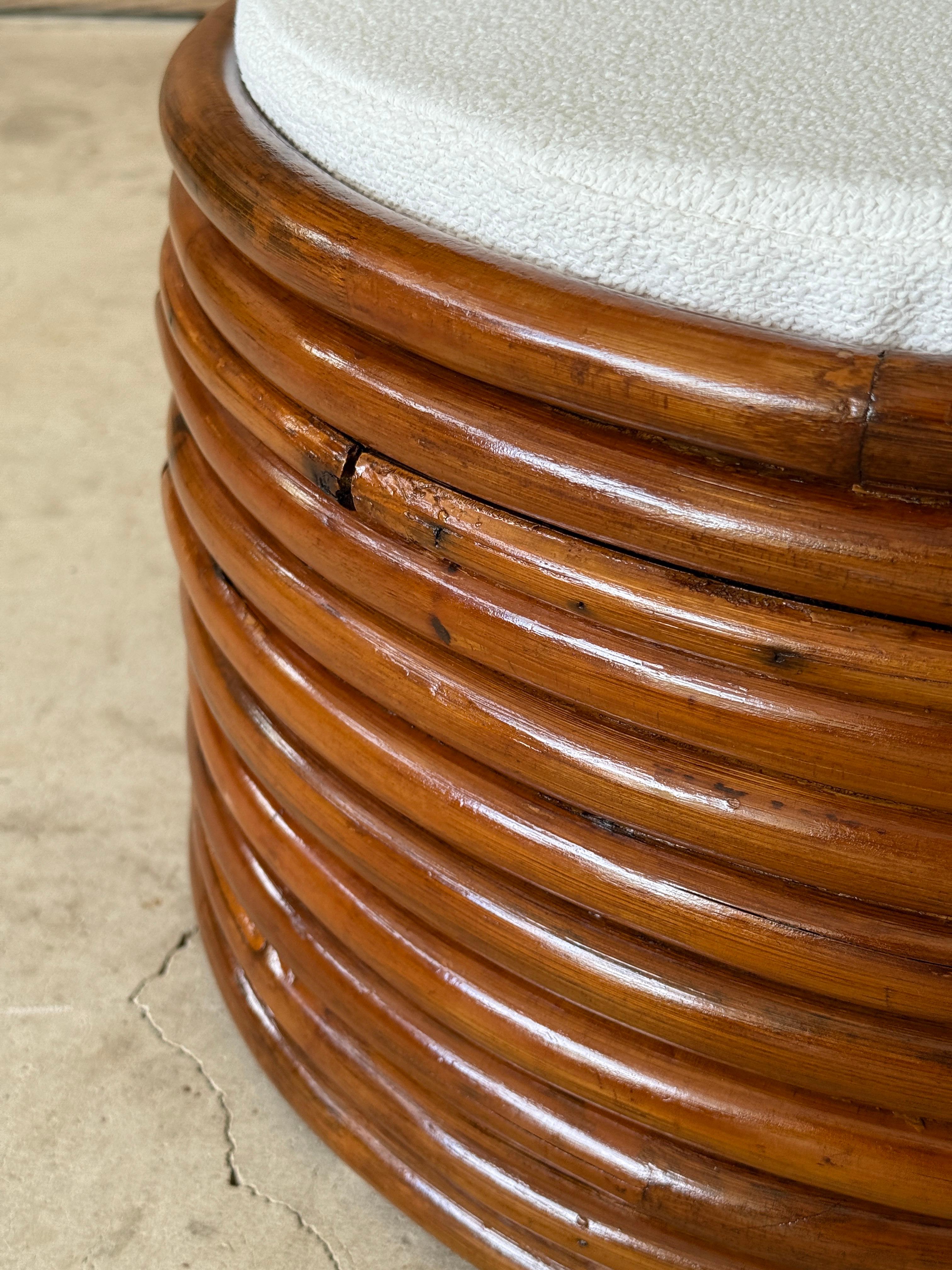 A sculptural pair of Mid-20th Century bent stacked rattan ottoman footstools in the manner of Paul Frankl. These vintage ottomans feature a rich honey-toned patina and distinctive horizontal banding, all fully refinished while preserving character