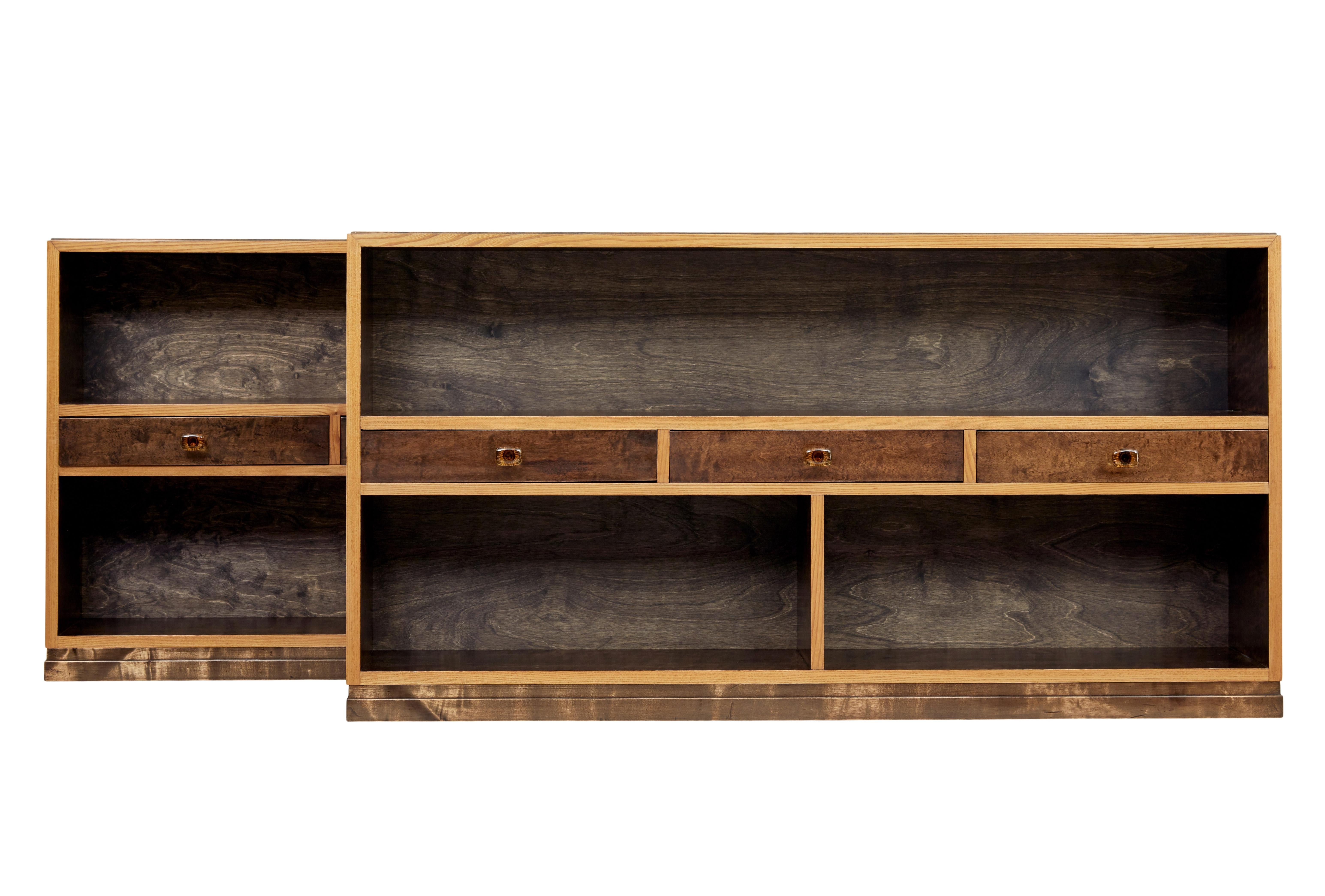 Pair of mid-20th century Scandinavian low open bookcases circa 1950.

Fine quality, and rare to find still as a pair. Made from contrasting light and dark stained birch timber.

Each with a central arrangement of 3 drawers fitted with cut glass