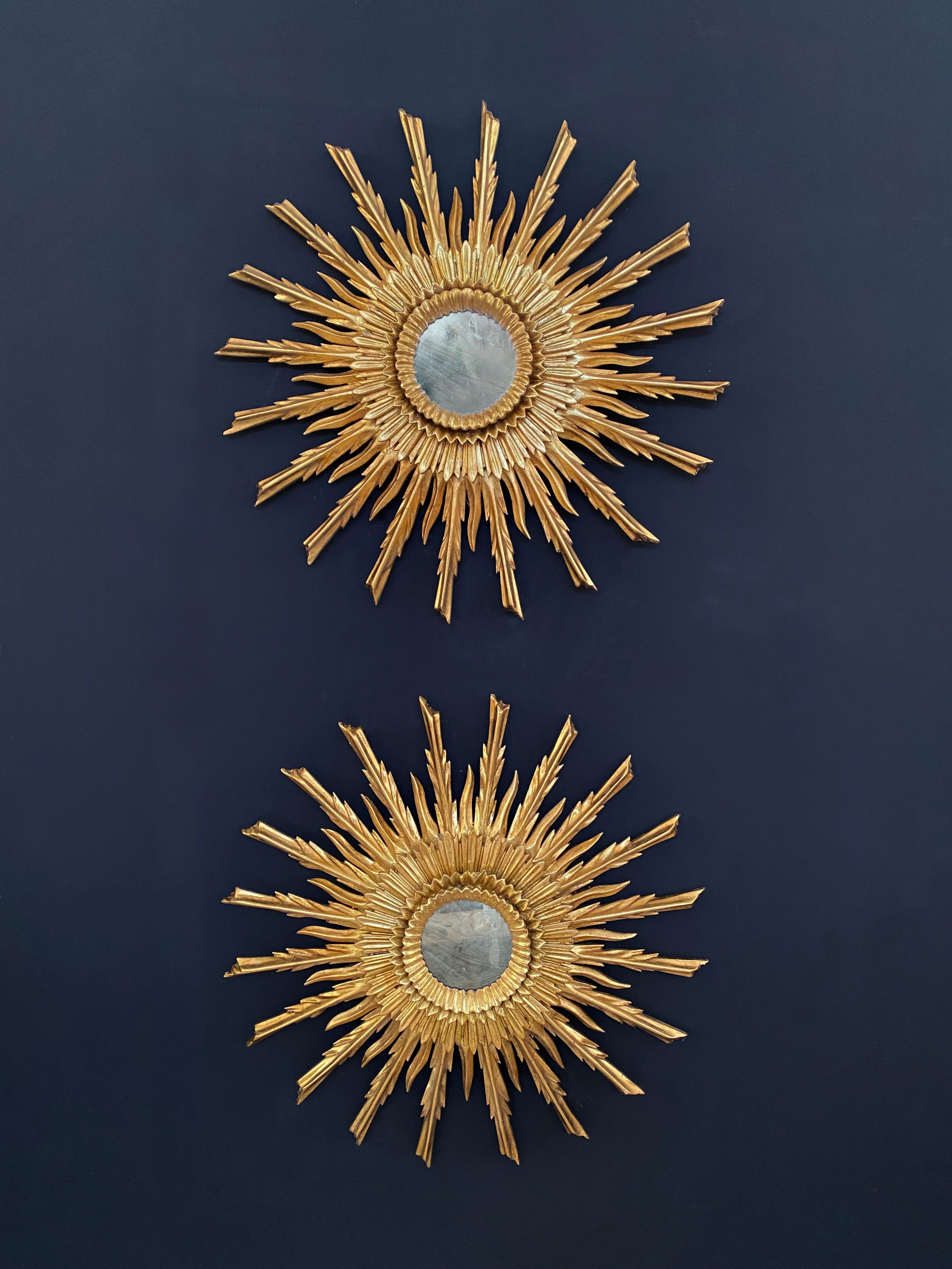 Maravilloso par de espejos dorados hechos a mano. Compuesto por varias filas de rayos de madera dorada. Cada rayo ha sido tallado individualmente y ha recibido un tratamiento artesanal a base de distintas capas de gesso y pulido final. Estas piezas