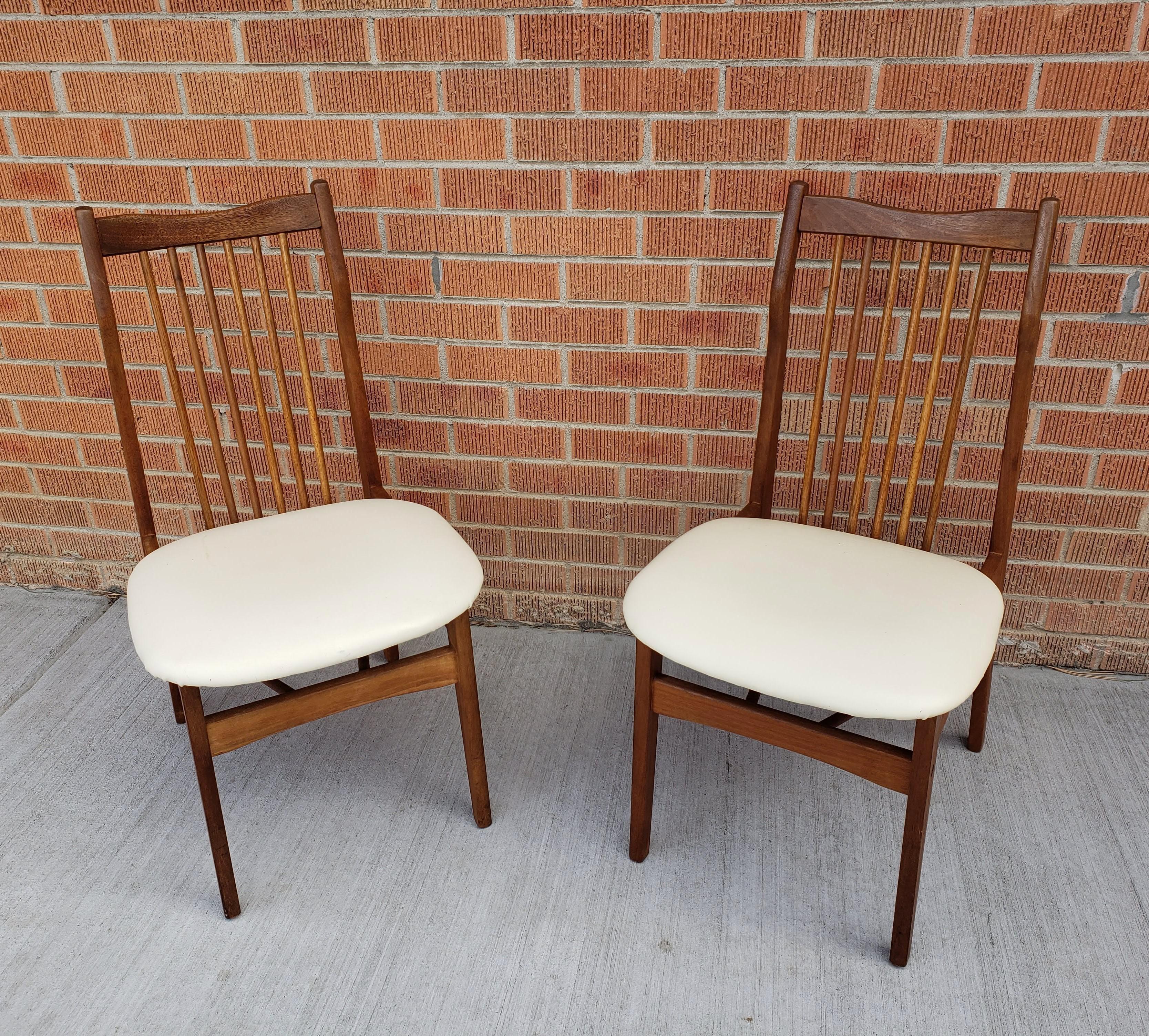 Pair of vintage Danish style mid-century dining chairs with lovely lines. The seats have their original coverings in a cream color in good condition. This material is durable and easy to clean.
