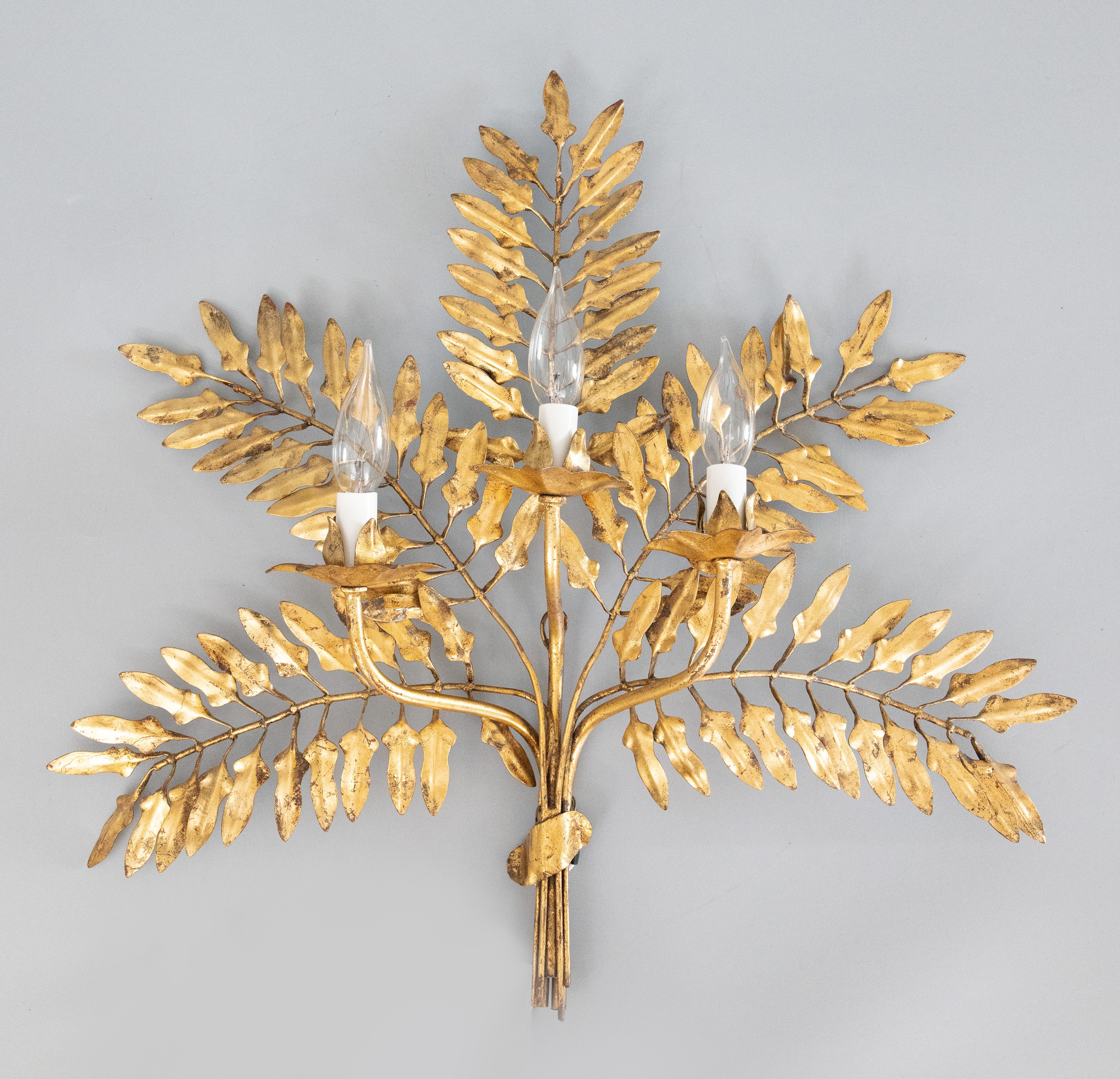 A gorgeous vintage pair of Italian gilded tole and crystal three light wall sconces. These stunning sconces have beautiful palm branches and leaves in a lovely gilt patina. They are in excellent working condition, ready to hang. Candelabra bulbs not