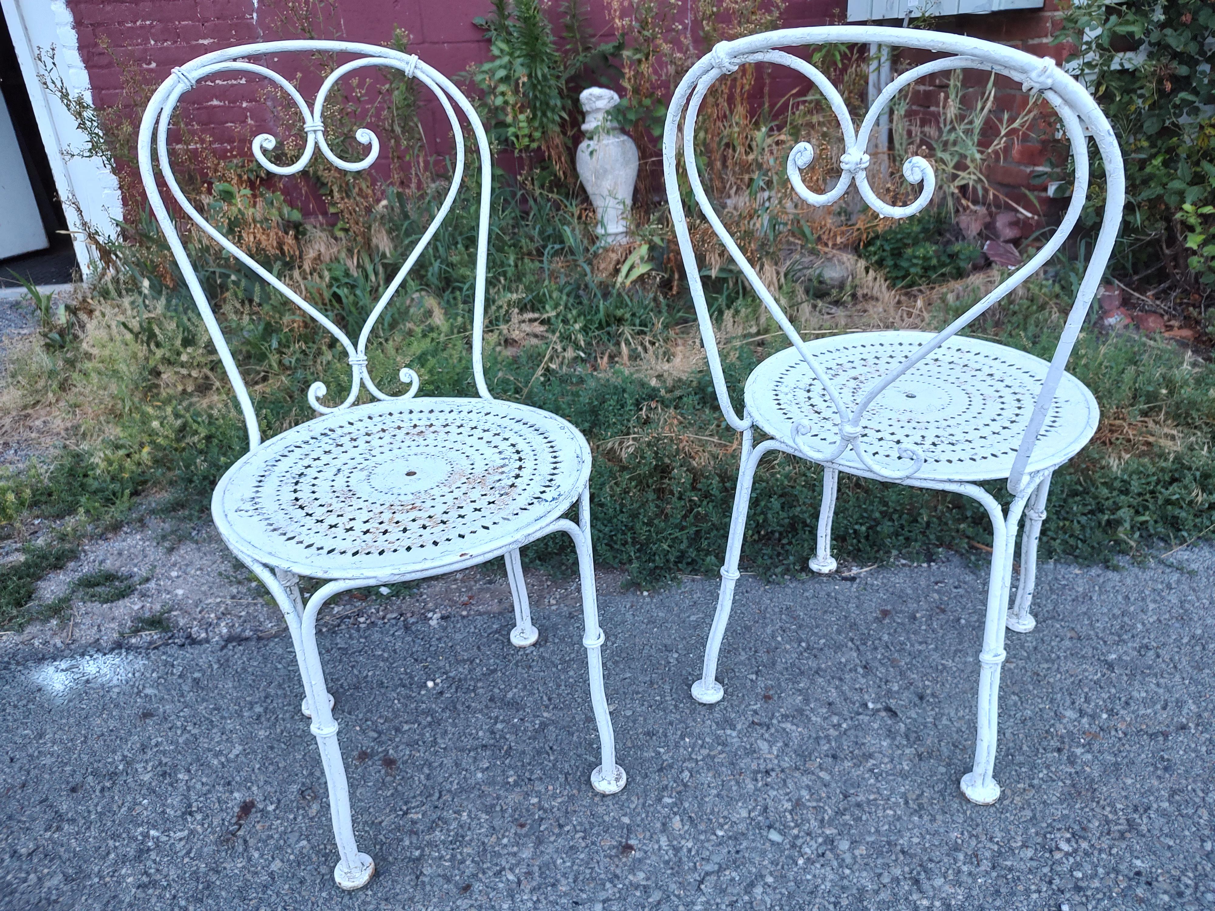 Fabulous pair of Mid Century French Iron chairs with pierced seats. Heart shaped backs side chairs with lots of character and patina. Priced and sold as a pair. Can be parcel posted. In excellent and sound antique condition, some peeling paint,