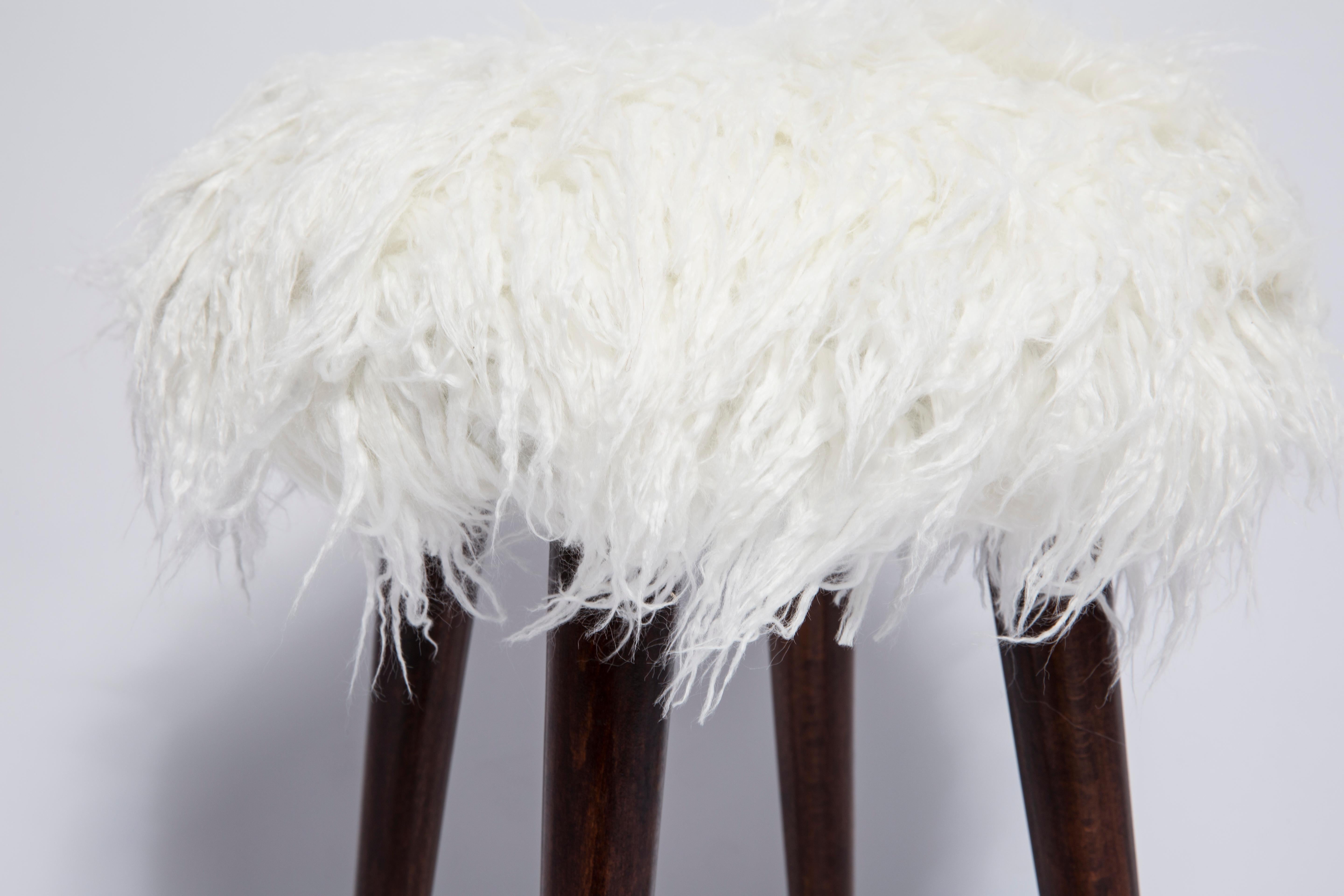 Stool from the turn of the 1960s and 1970s. 

Beautiful white faux fur white upholstery. 

The stool consists of an upholstered part, a seat and wooden legs narrowing downwards, characteristic of the 1960s style. 

We can prepare this stool also in